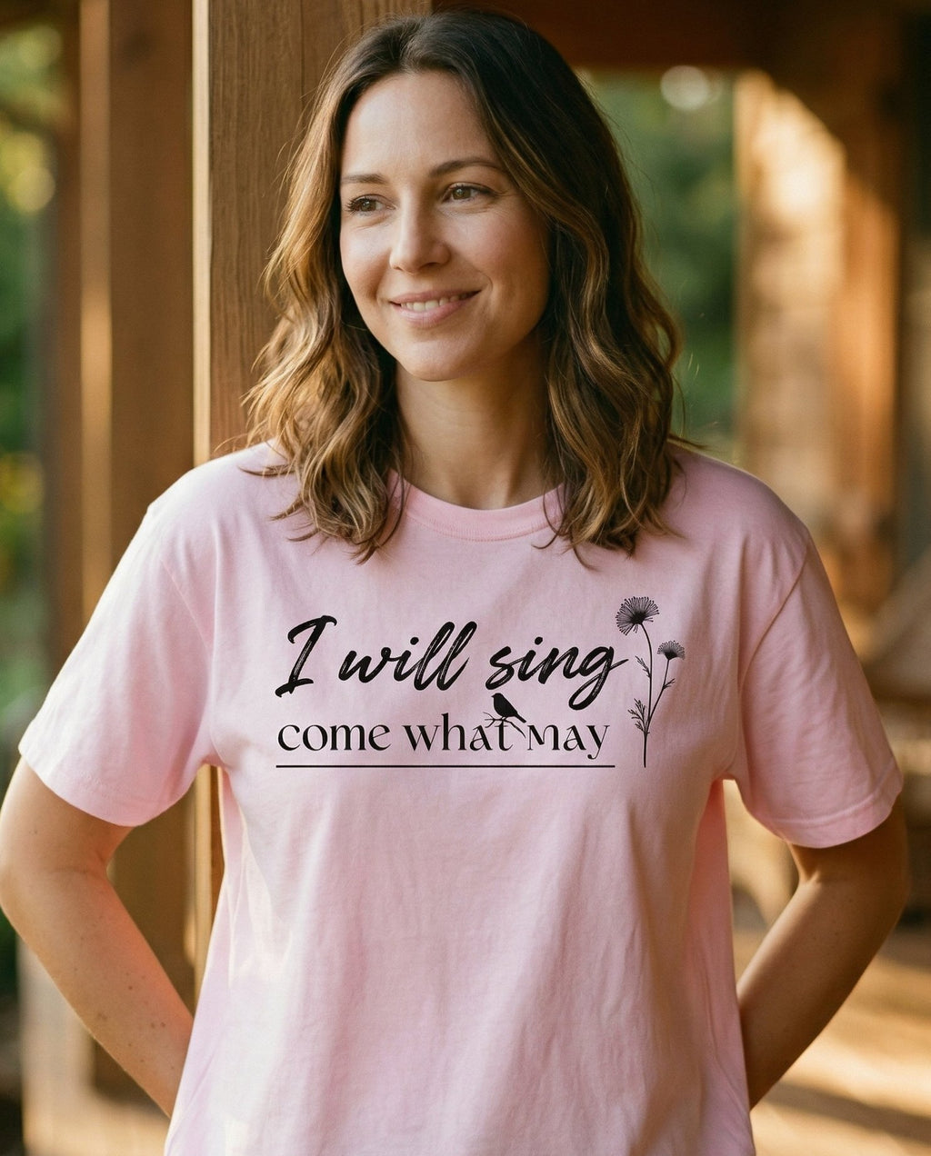 I Will Sing – Blossom women's Christian tee, lifestyle photo in sunny porch – Elegant script 'I will sing come what may' with a small wildflower ste – She Wears Faith