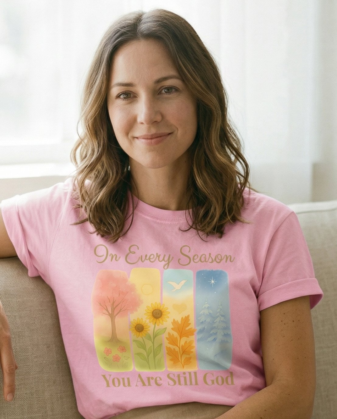 In Every Season – Blossom women's Christian tee, lifestyle photo in cozy living room – Four vertical panels depicting each season (spring tree – She Wears Faith
