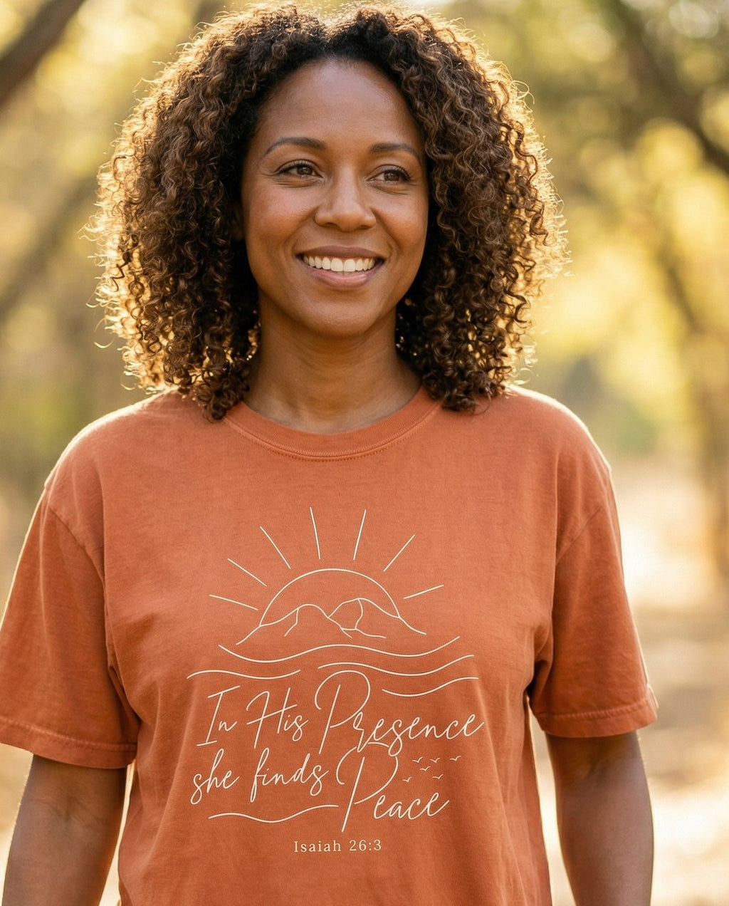 She Finds Peace – Yam women's Christian tee, lifestyle photo in nature trail – Minimalist line-art sunrise over mountain waves with 'In His Presence  – Isaiah 26:3 – She Wears Faith