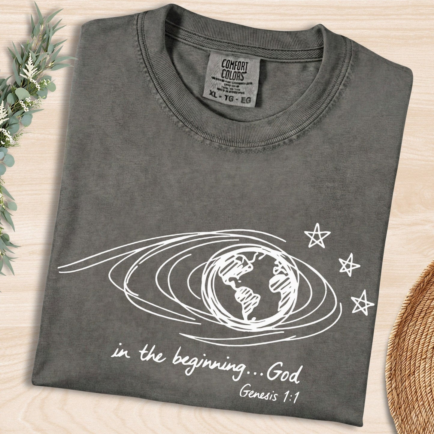 Pepper Grey Comfort Colors 1717 tshirt displaying a white scribble earth graphic and "In the beginning... God" text. High-quality Christian women tee with a retro look, popular in US faith wear shops.