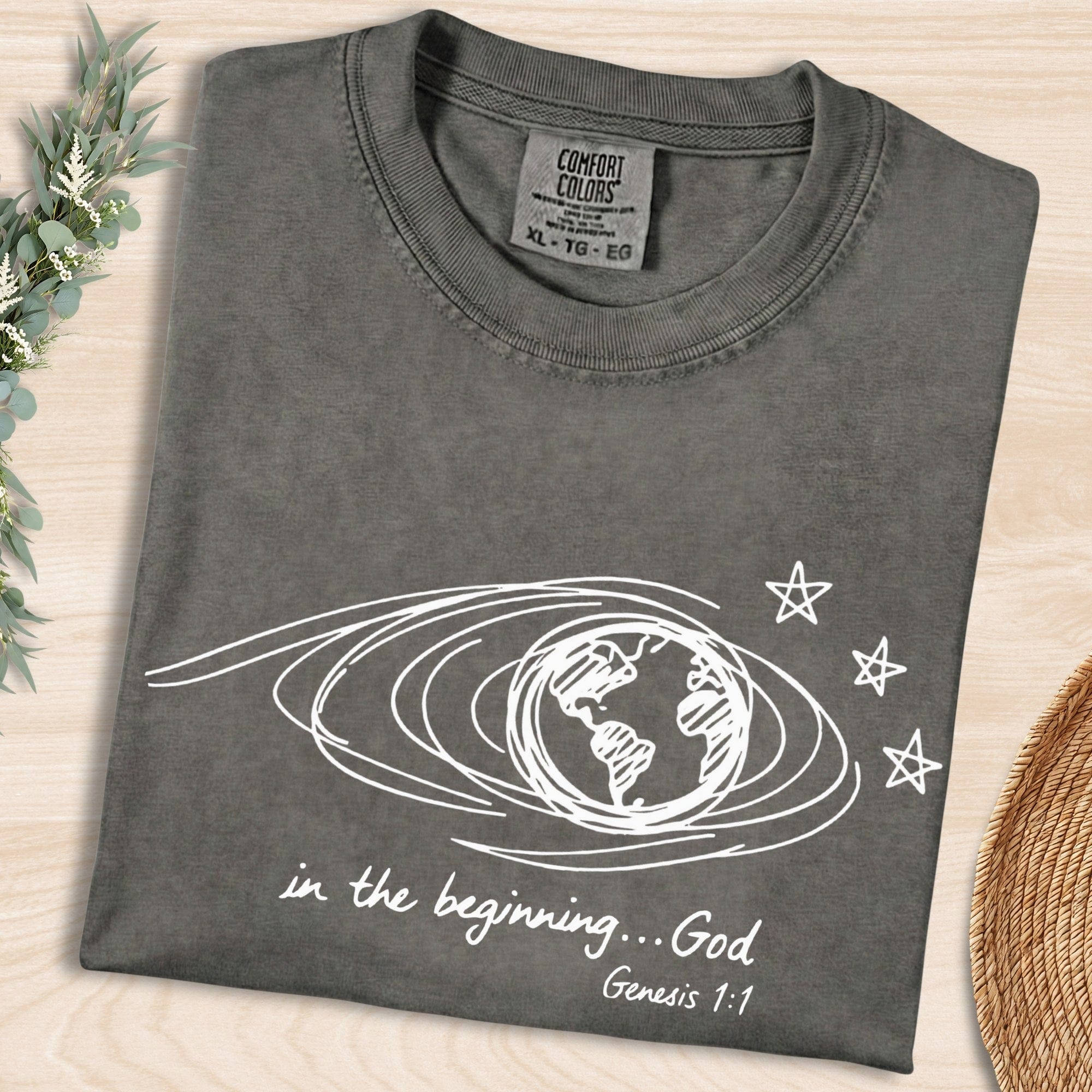 Pepper Grey Comfort Colors 1717 tshirt displaying a white scribble earth graphic and "In the beginning... God" text. High-quality Christian women tee with a retro look, popular in US faith wear shops.