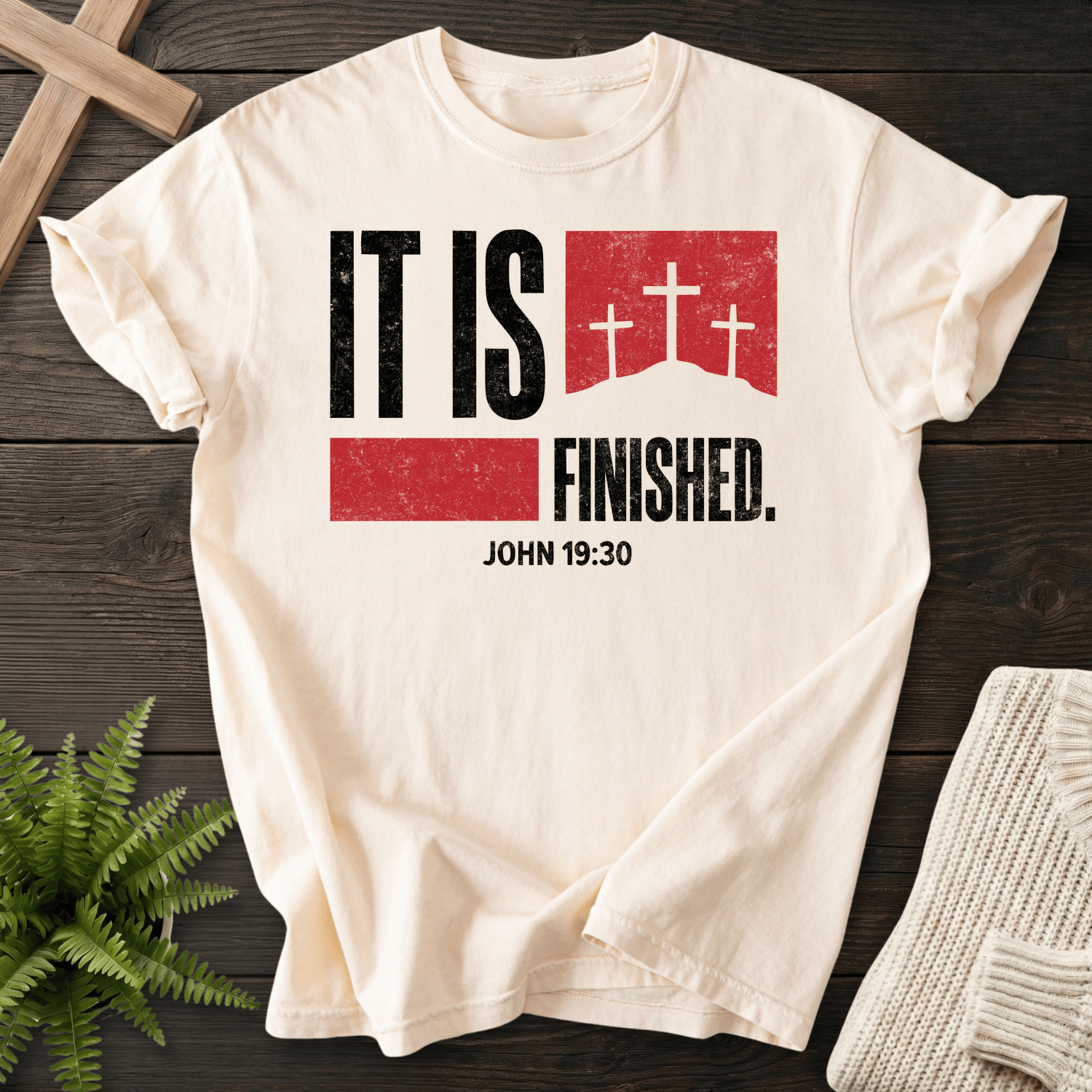 Ivory women's Christian t-shirt with bold "It Is Finished" text and three crosses in a red banner, inspired by John 19:30