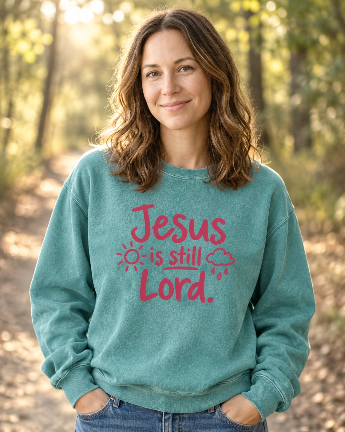 Jesus Is Still Lord, Seafoam women's Christian sweatshirt, lifestyle photo in nature trail, Jesus is still Lord lettering with a sun and rain cloud, She Wears Faith