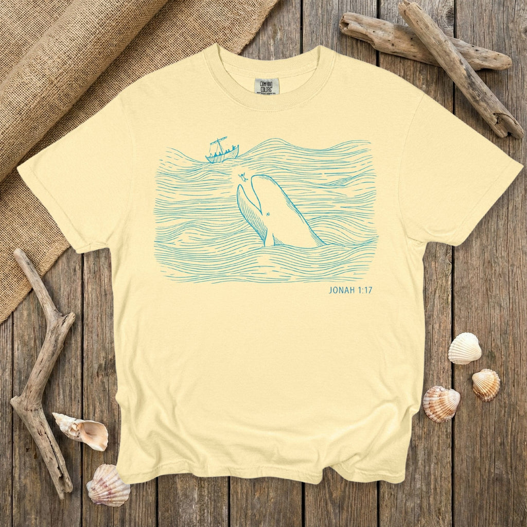 Comfort Colors 1717 butter yellow Christian women tee displaying a blue line-art illustration of Jonah and the great fish from Jonah 1:17. A bright and uplifting scripture-themed T-shirt designed for US faith wear and Christian women who enjoy playful Bible-story artwork.
