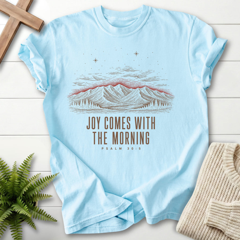 Flatlay of a Chambray Christian t-shirt for women with mountain graphic with "Joy Comes With the Morning Mountain T-Shirt" Psalm 30:5.