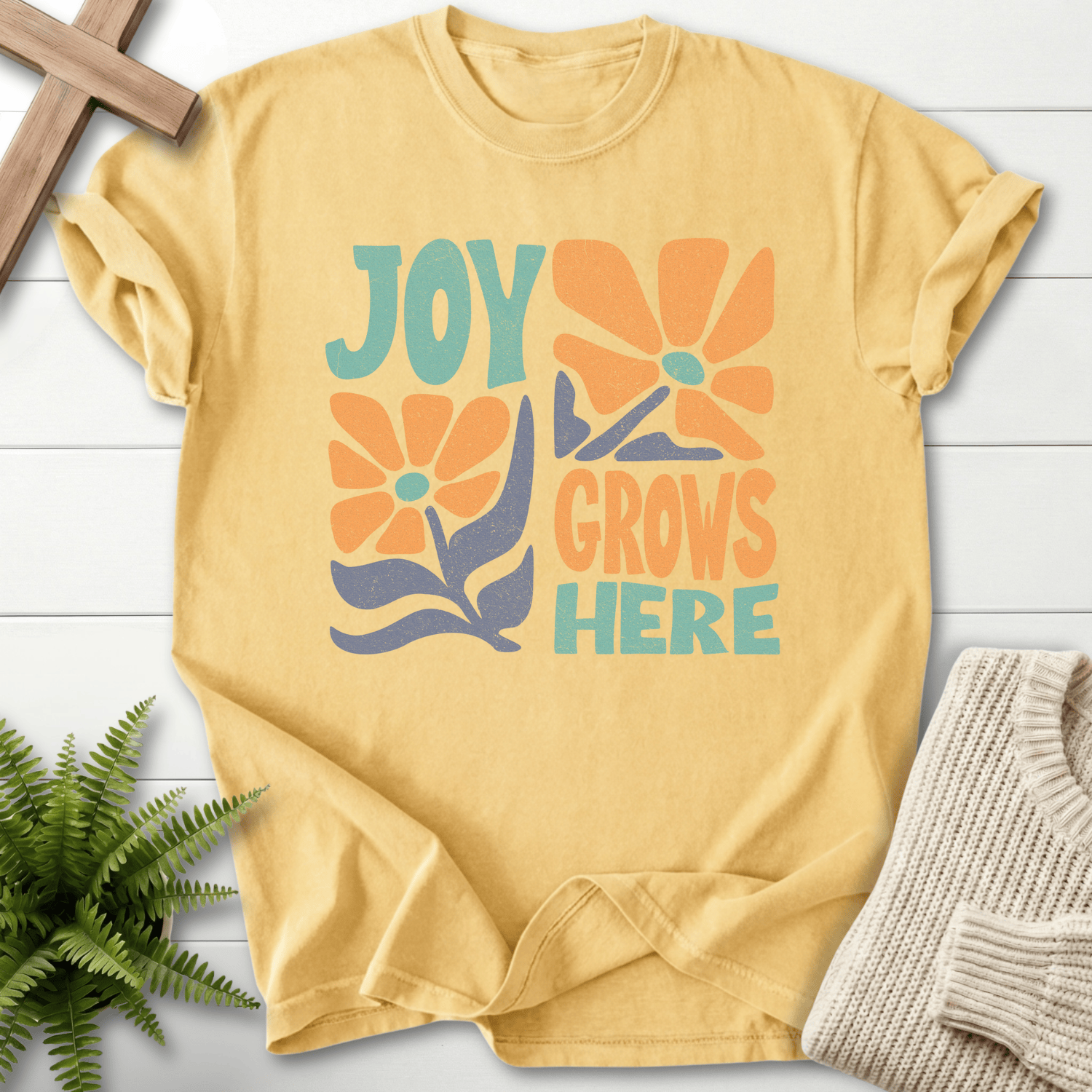 Butter women's Christian t-shirt with retro "Joy Grows Here" teal and orange floral graphics