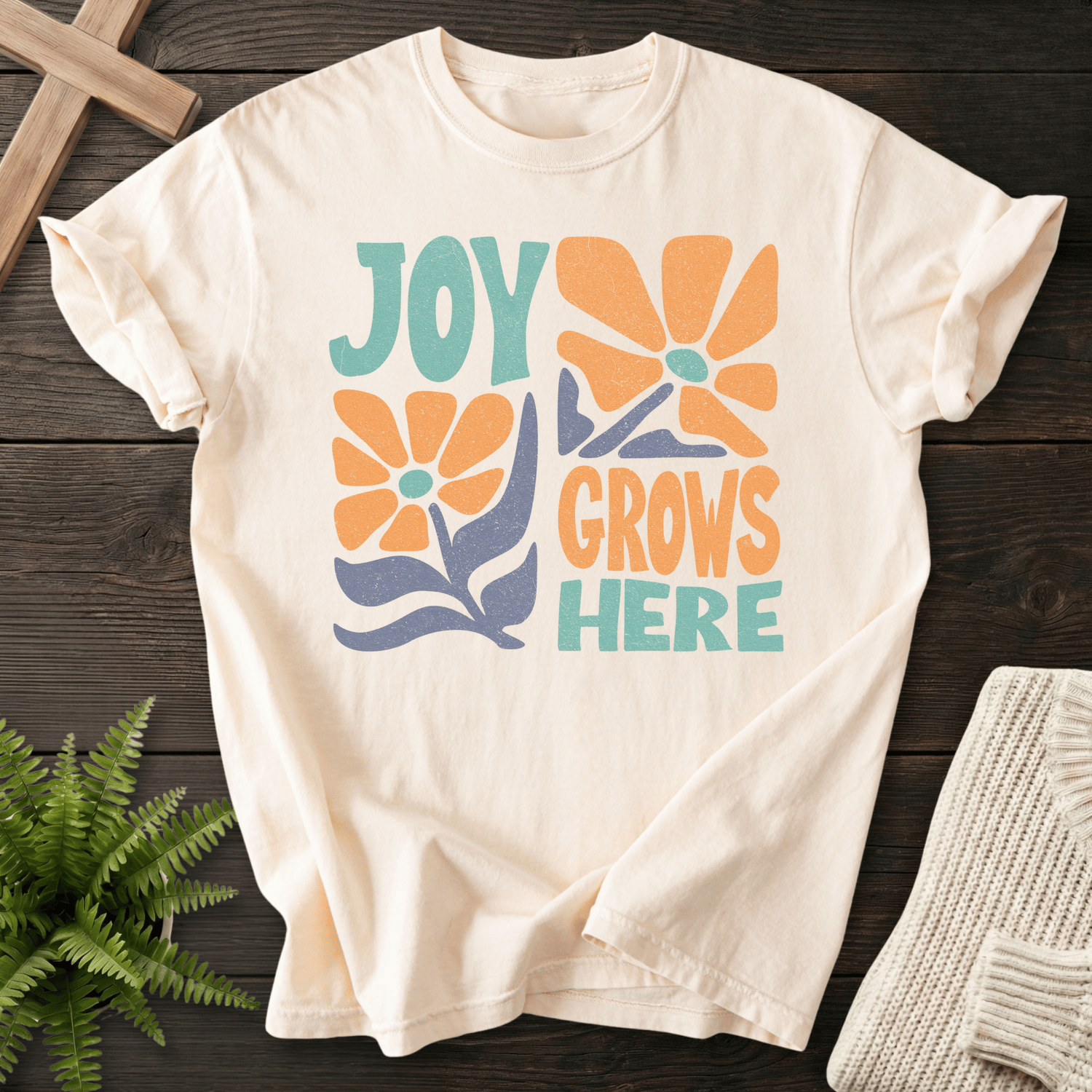 Ivory women's Christian t-shirt with groovy "Joy Grows Here" orange daisy flowers and teal block text