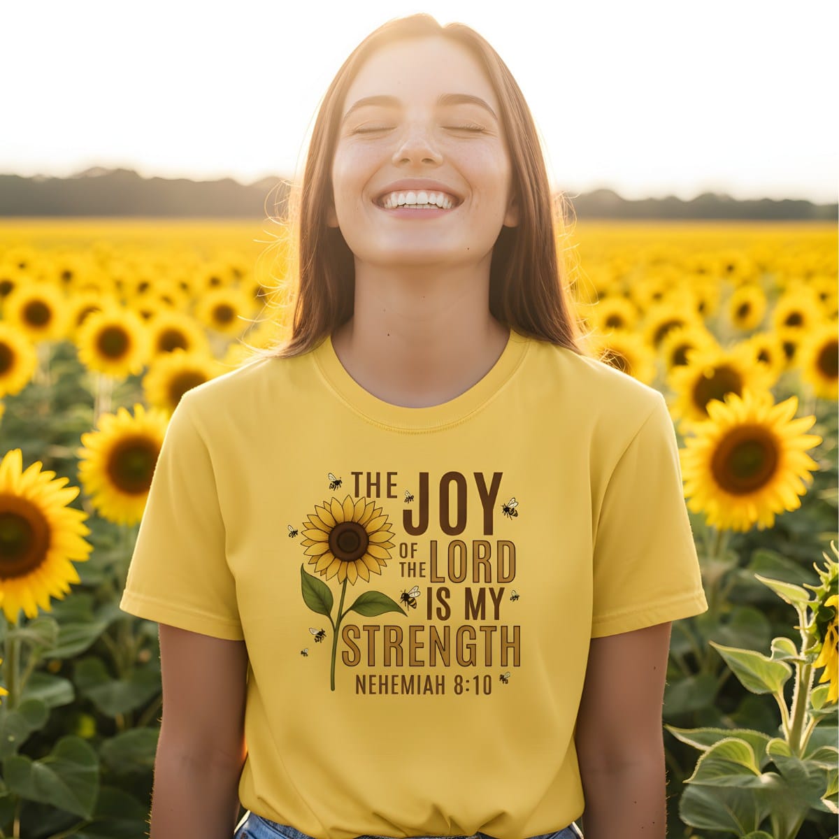Smiling woman standing in a sunflower field wearing a Comfort Colors 1717 citrus “The Joy of the Lord Is My Strength – Nehemiah 8:10” t-shirt featuring a sunflower and bee design. A cheerful women’s scripture tee — modern Christian shirt and uplifting faith-based apparel for women, perfect Christian mom gift idea.