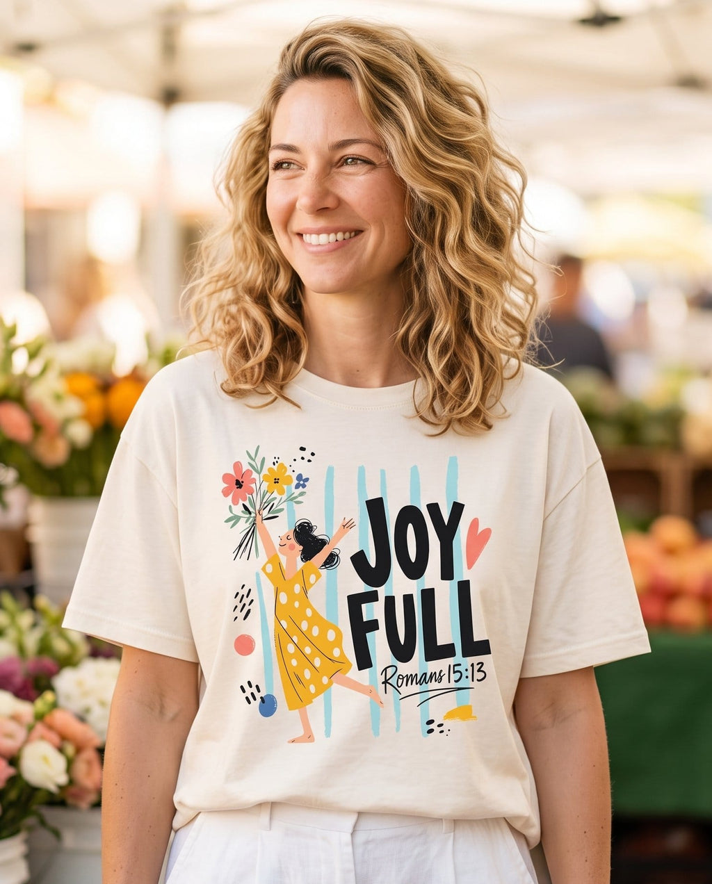 Joyfull In Hope Romans 15:13 – Ivory women's Christian tee, lifestyle photo in farmers market – Dancing woman in a polka-dot dress lifting a bouquet overhead – Romans 15:13 – She Wears Faith