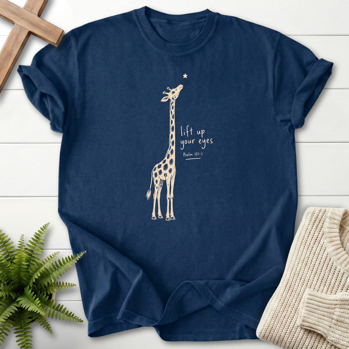 Flat lay of a Navy Scripture shirt featuring "Lift Up Your Eyes Giraffe T-Shirt" Psalm 121:1.