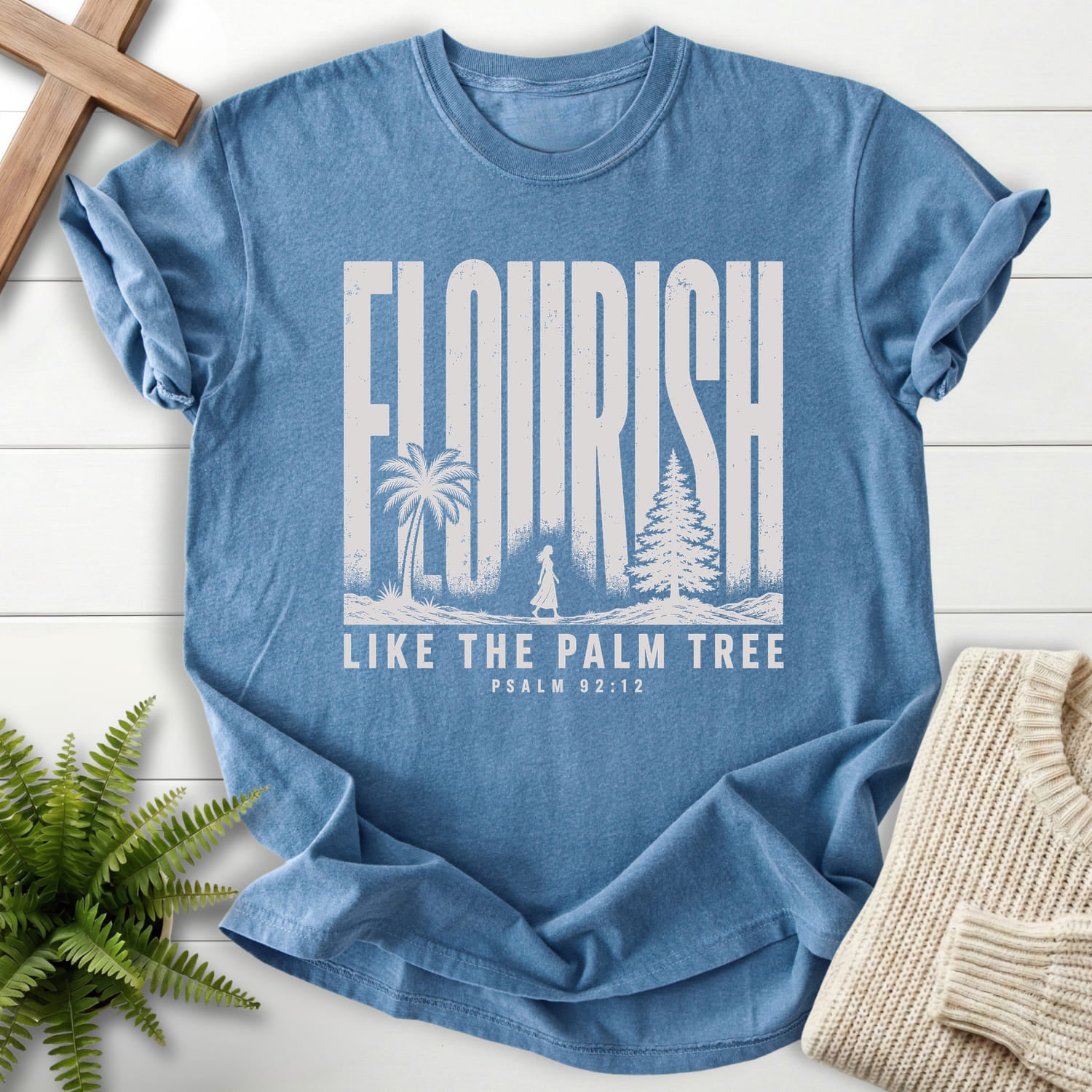 Flatlay of a Blue Jean Scripture shirt with "Like The Palm Flourish Scripture T-Shirt" Psalm 92:12.