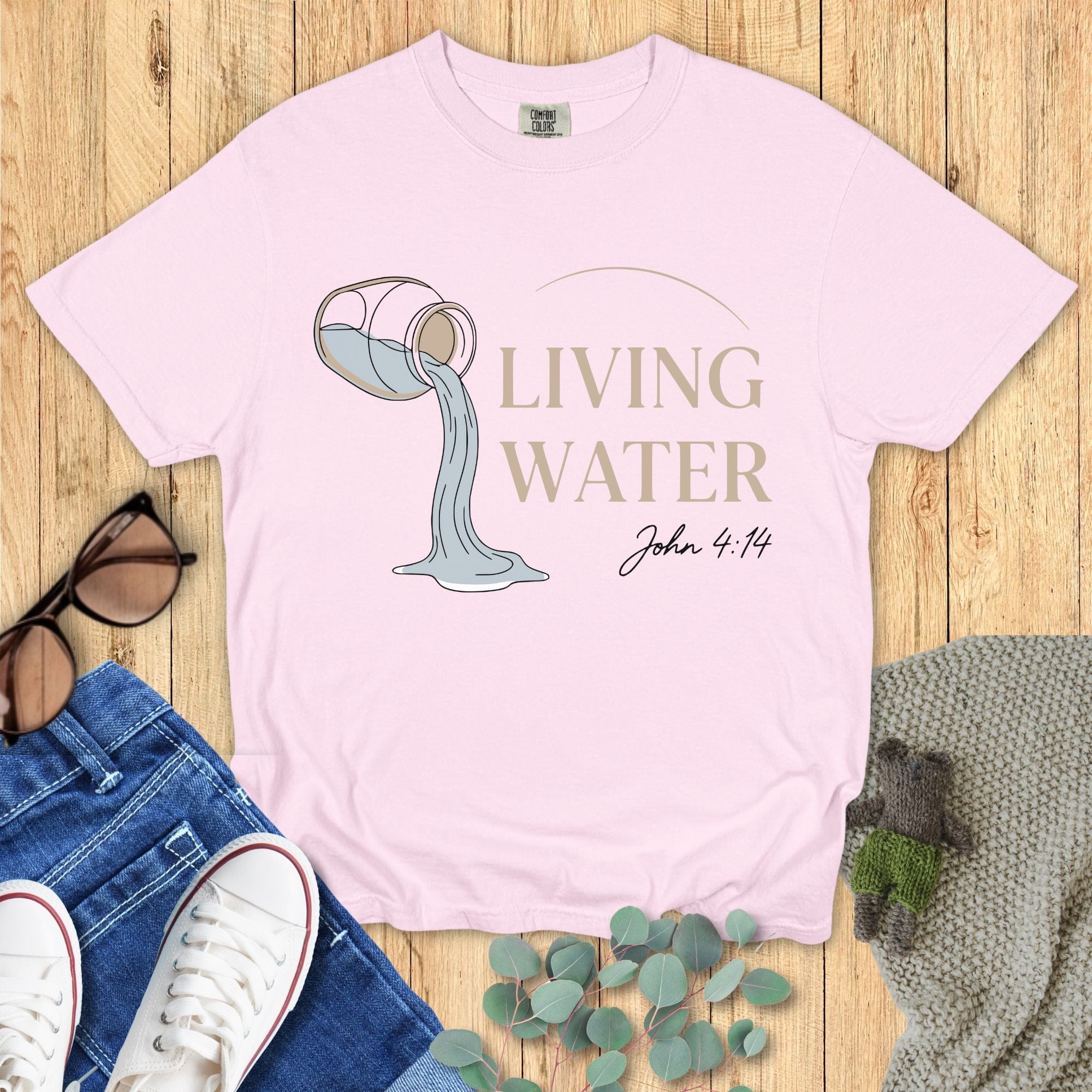 Comfort Colors 1717 blossom “Living Water – John 4:14” t-shirt in soft pink with clean line art of a pouring jug. A gentle women’s scripture tee — uplifting faith-based apparel for women and pretty modern Christian shirt, ideal for Christian mom gift ideas.