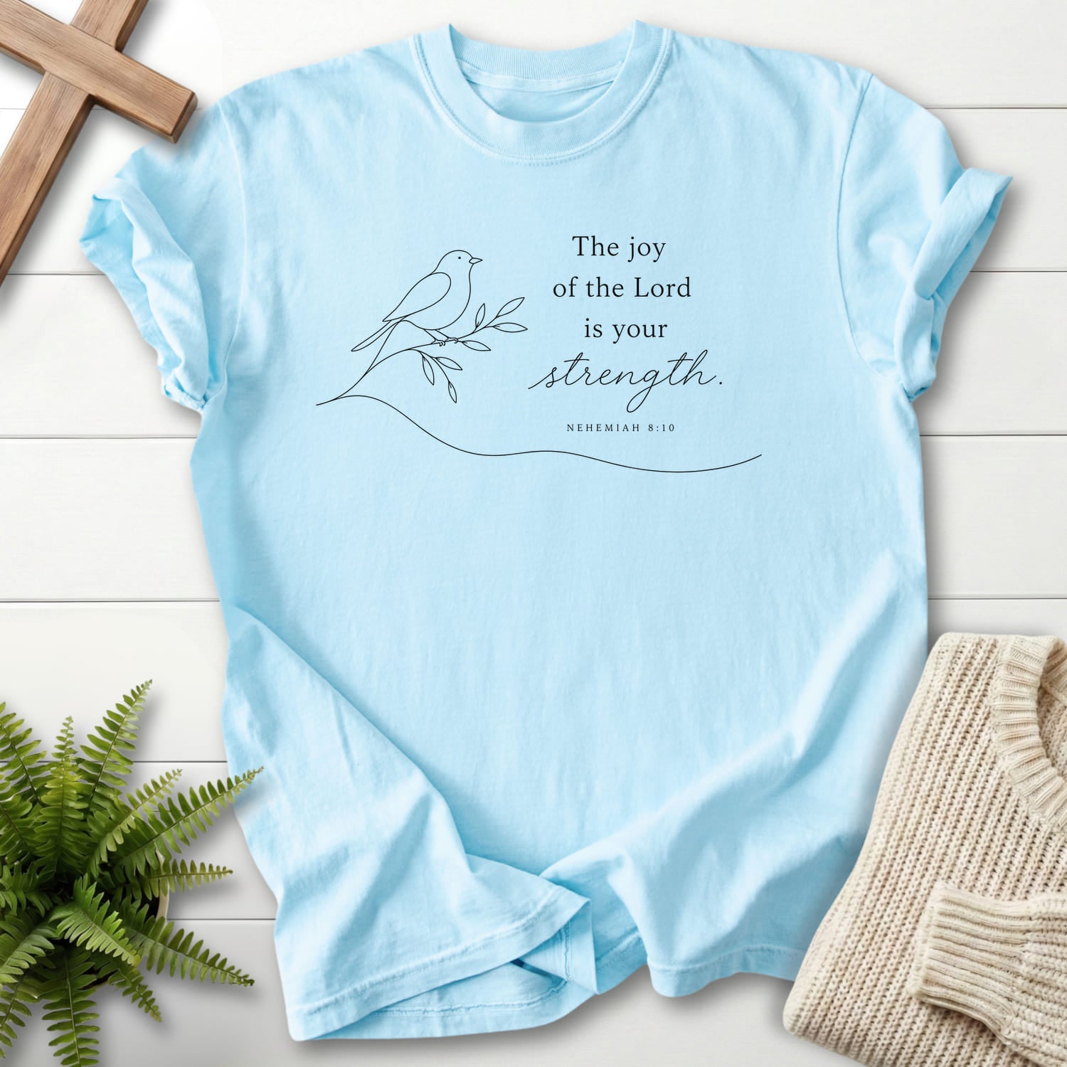 Flatlay of a Chambray Christian graphic tee with minimalist design with "Lord is your Strength T-Shirt" Nehemiah 8:10.