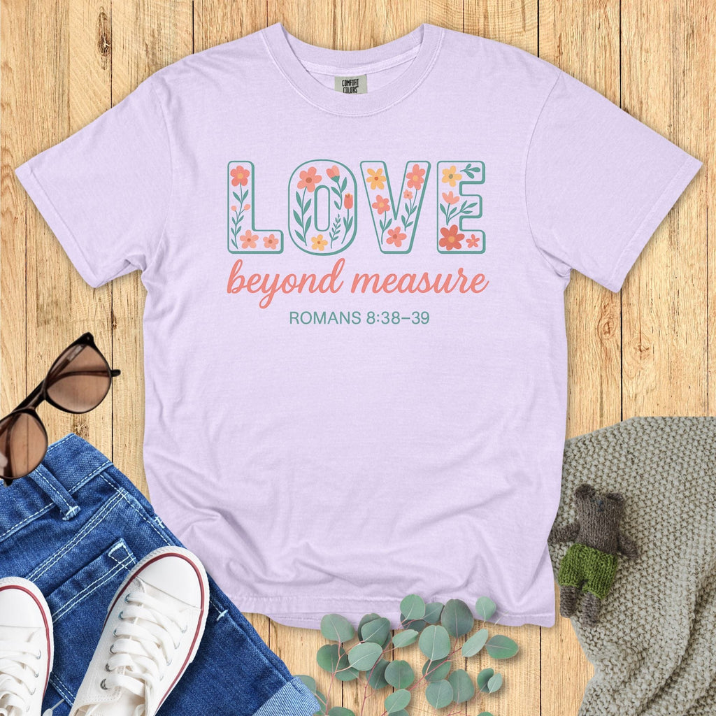 Orchid purple Comfort Colors Christian T-shirt featuring floral block letter "LOVE," phrase "beyond measure," and scripture Romans 8:38–39. Religious inspirational graphic tee flat lay styled with denim and accessories.