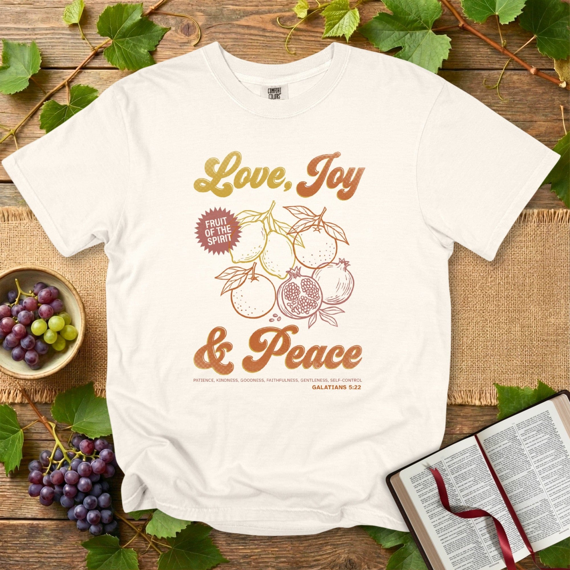 Comfort Colors 1717 ivory Christian women tee displaying Fruit of the Spirit graphics and the message Love, Joy & Peace from Galatians 5:22. Stylish US faith wear with soft, uplifting Christian artwork