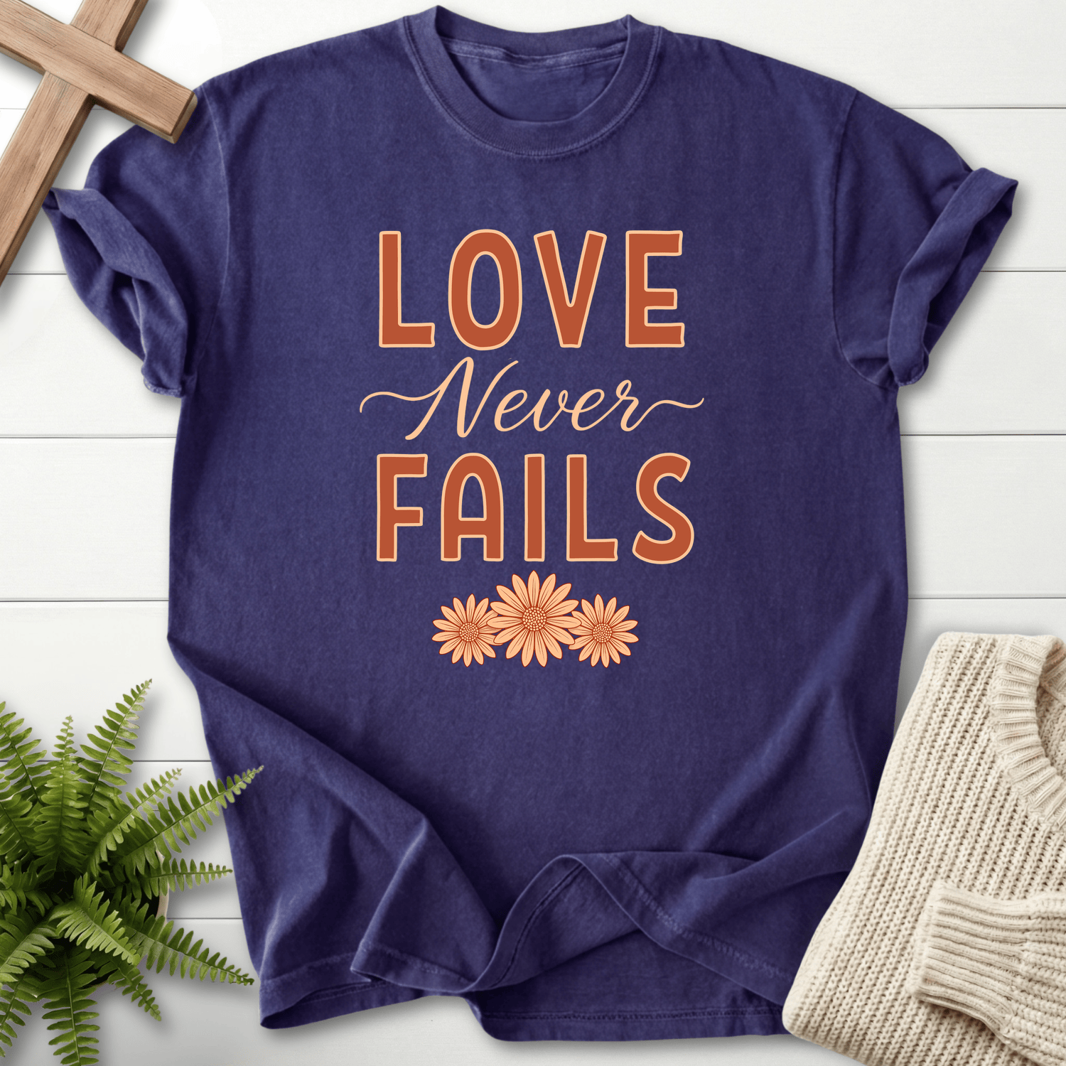Grape women's faith t-shirt with bold text and daisy flowers, inspired by 1 Corinthians 13:8.