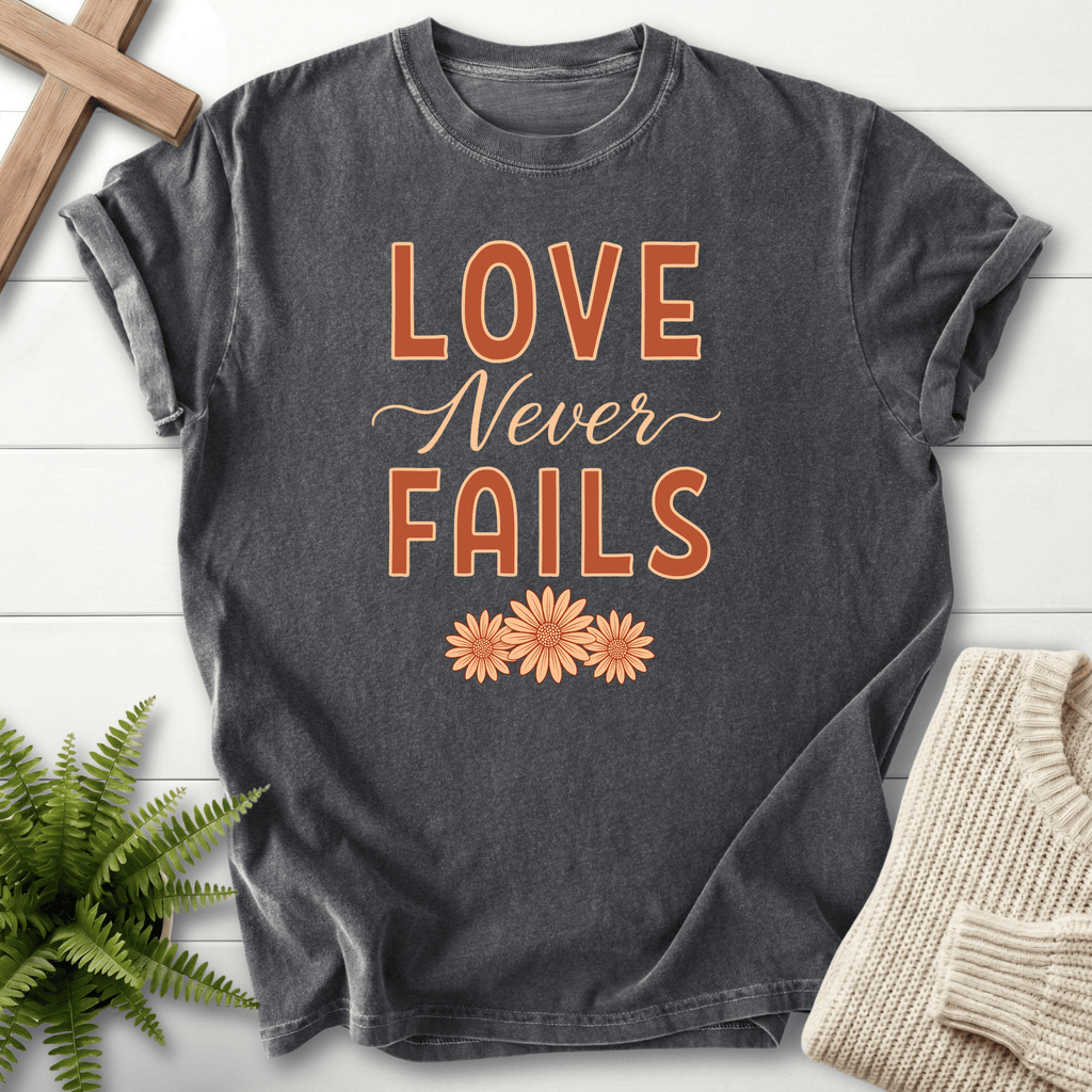 Pepper garment-dyed Christian t-shirt with "Love Never Fails" floral script, inspired by 1 Corinthians 13:8.