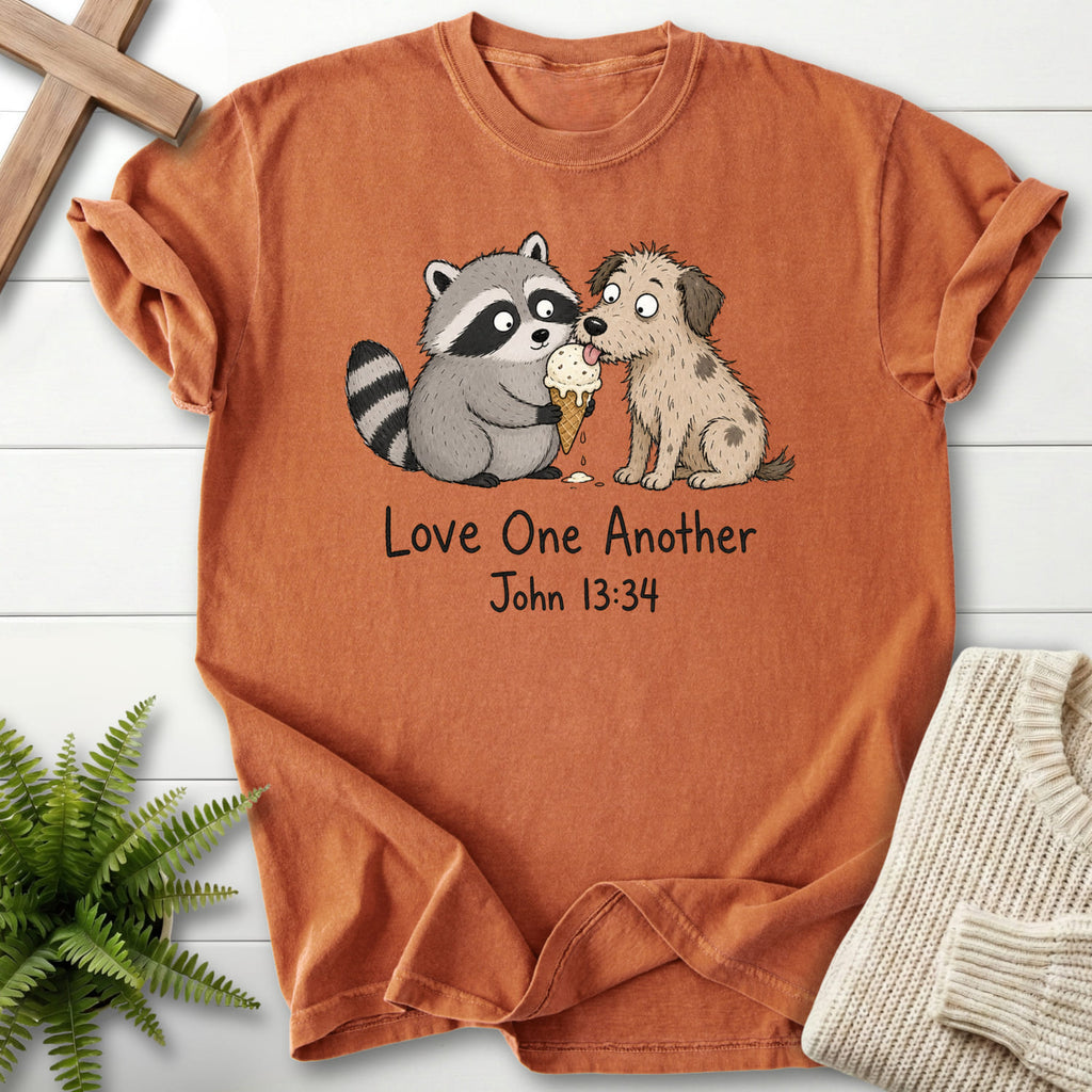 Flat lay of a Yam Bible verse tee featuring "Love One Another Raccoon Puppy T-Shirt" John 13:34.