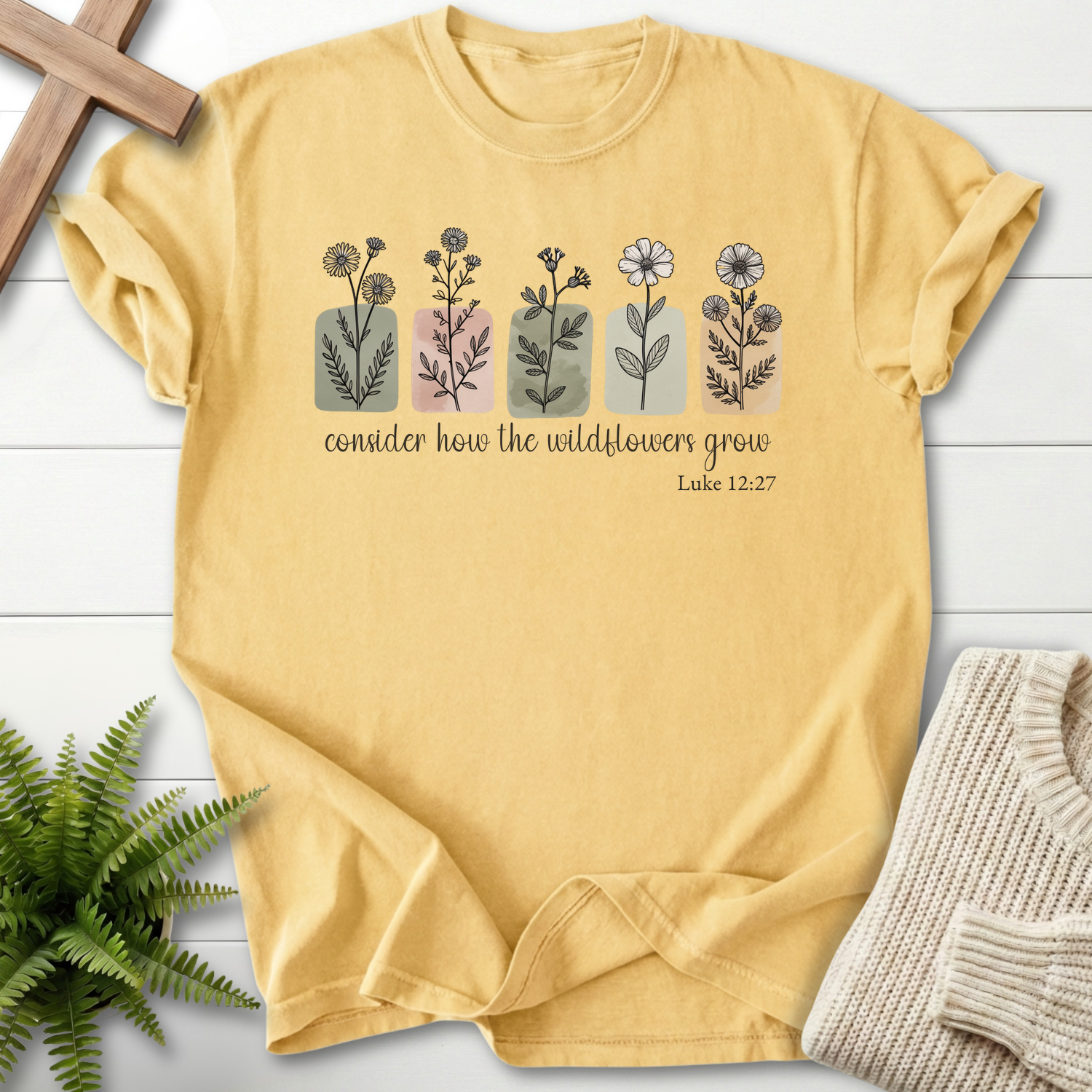 Butter women's Christian t-shirt with watercolor wildflower row, inspired by Luke 12:27.