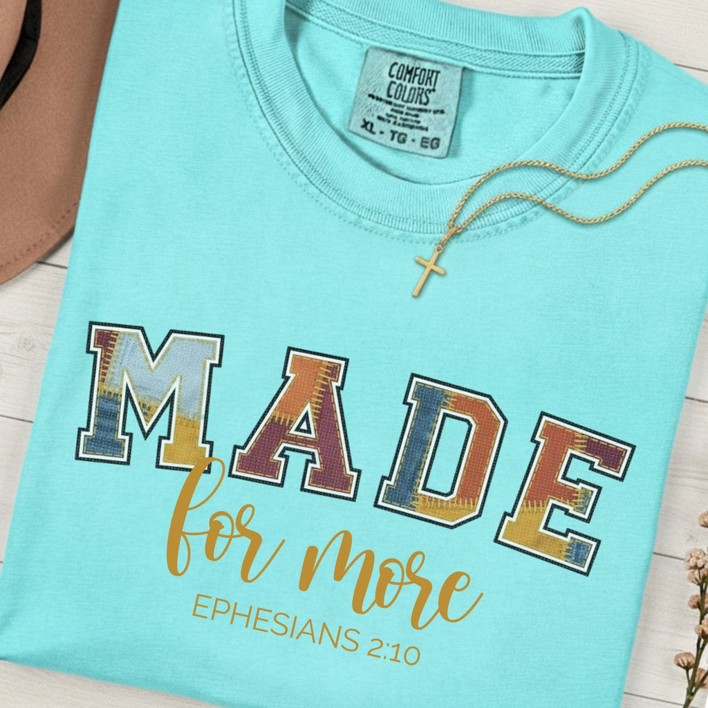 Flatlay of a Comfort Colors 1717 chalky mint “Made for More” Ephesians 2:10 t-shirt with bold multicolor applique-style text and elegant script. A cheerful women’s scripture tee  - faith-based apparel for women and modern Christian shirt, uplifting Christian mom gift idea that celebrates identity in Christ.