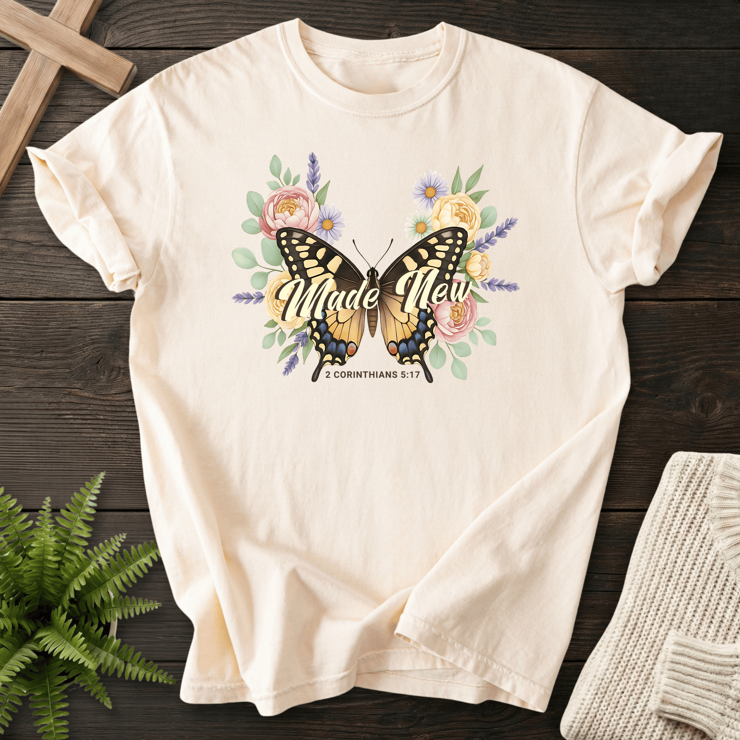 Ivory women's Christian t-shirt with a large watercolor butterfly and floral blooms, inspired by 2 Corinthians 5:17.