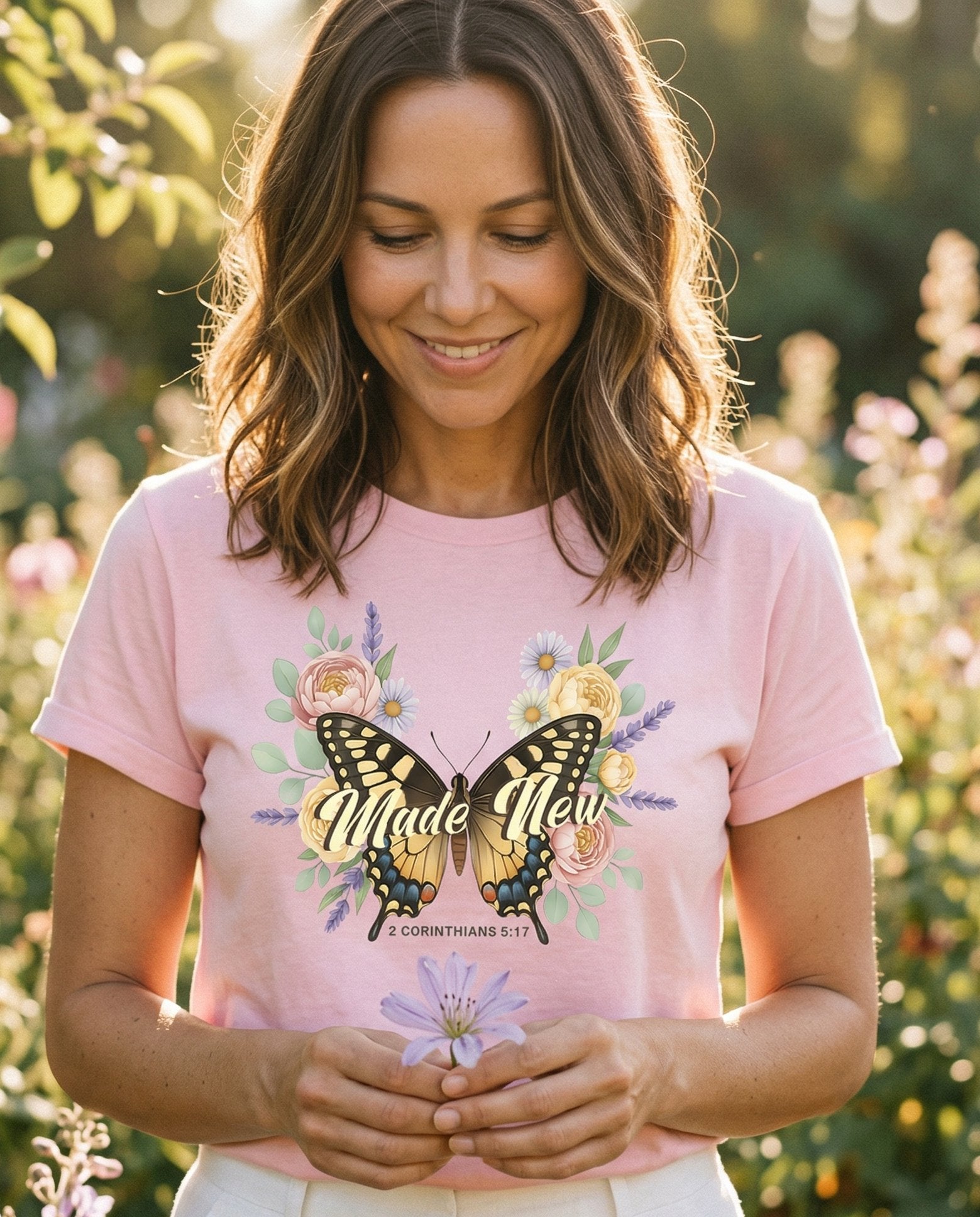Made New Butterfly – Blossom women's Christian tee, lifestyle photo in outdoor garden – Large swallowtail butterfly illustration with script 'Made New' writte – 2 Corinthians 5:17 – She Wears Faith