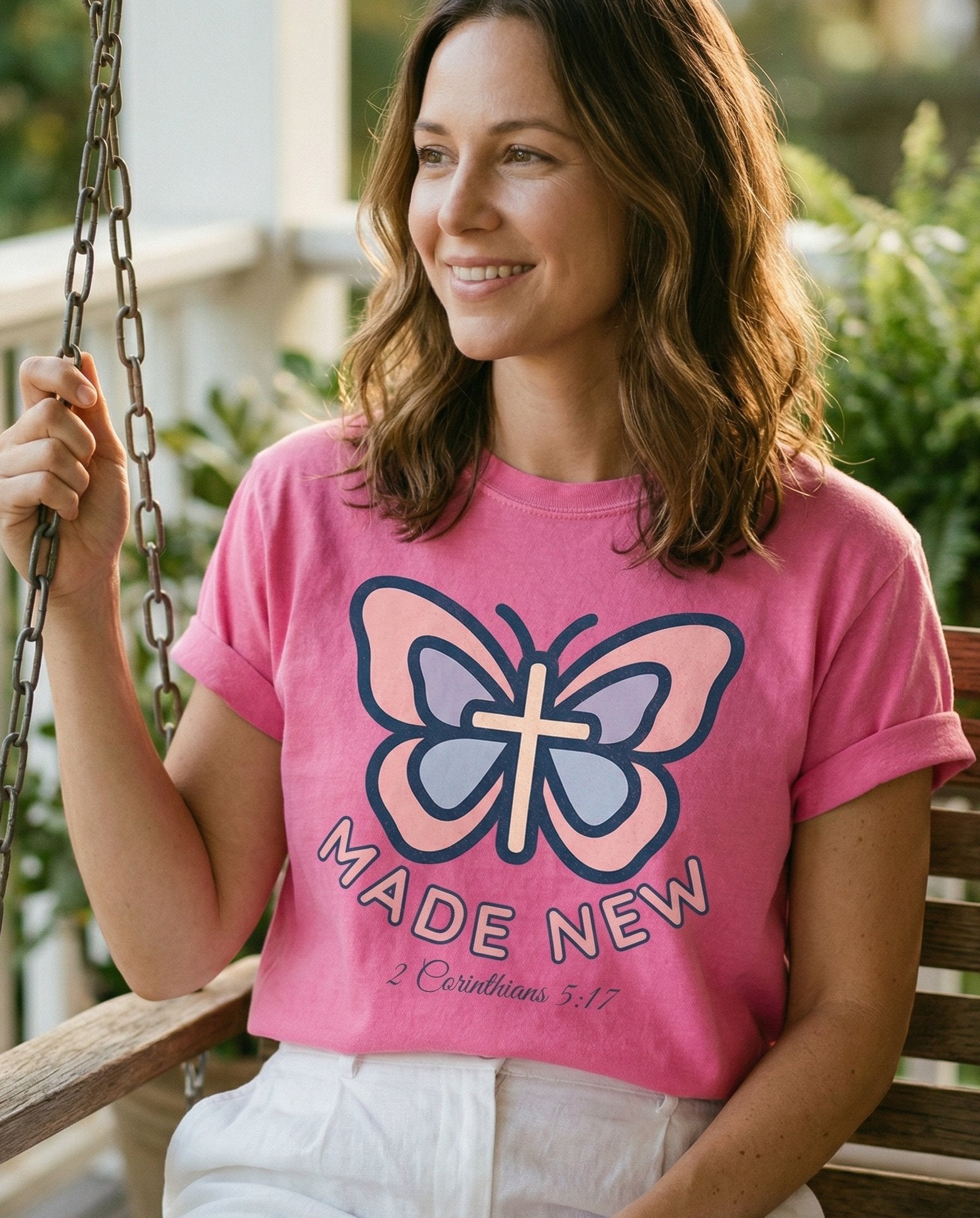 "Made New" Butterfly Christian – Crunchberry women's Christian tee, lifestyle photo in sunny porch – Stylized butterfly illustration with a cross in the body center – 2 Corinthians 5:17 – She Wears Faith
