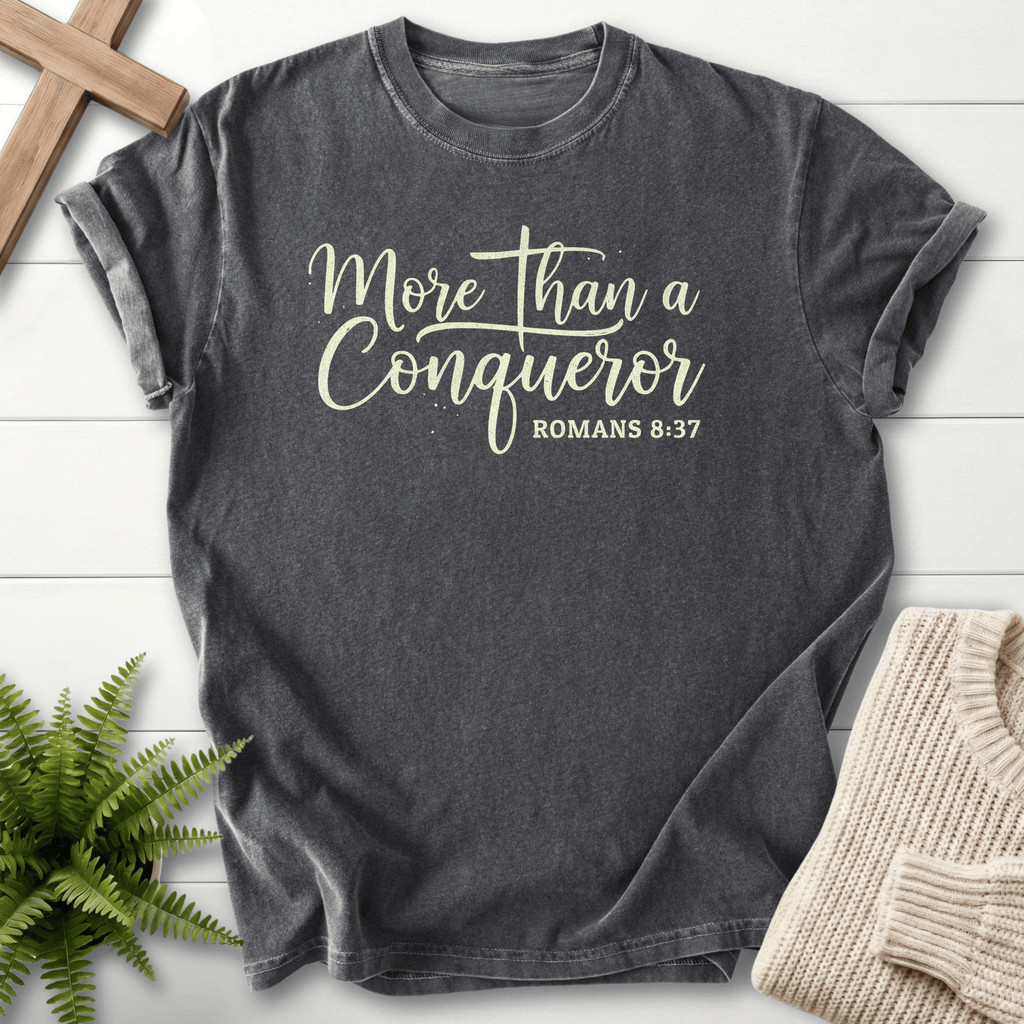 Pepper grey women's Christian t-shirt with cursive 'More Than a Conqueror' script, inspired by Romans 8:37.