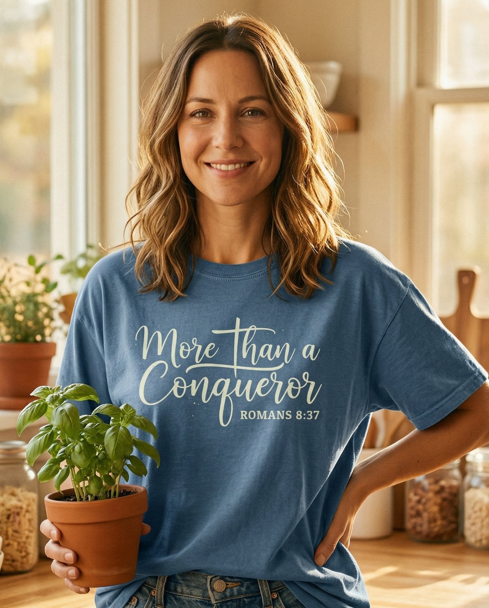 More Than a Conqueror – Blue Jean women's Christian tee, lifestyle photo in morning kitchen setting – Elegant cursive script reading 'More Than a Conqueror' with Romans 8:3 – Romans 8:37 – She Wears Faith