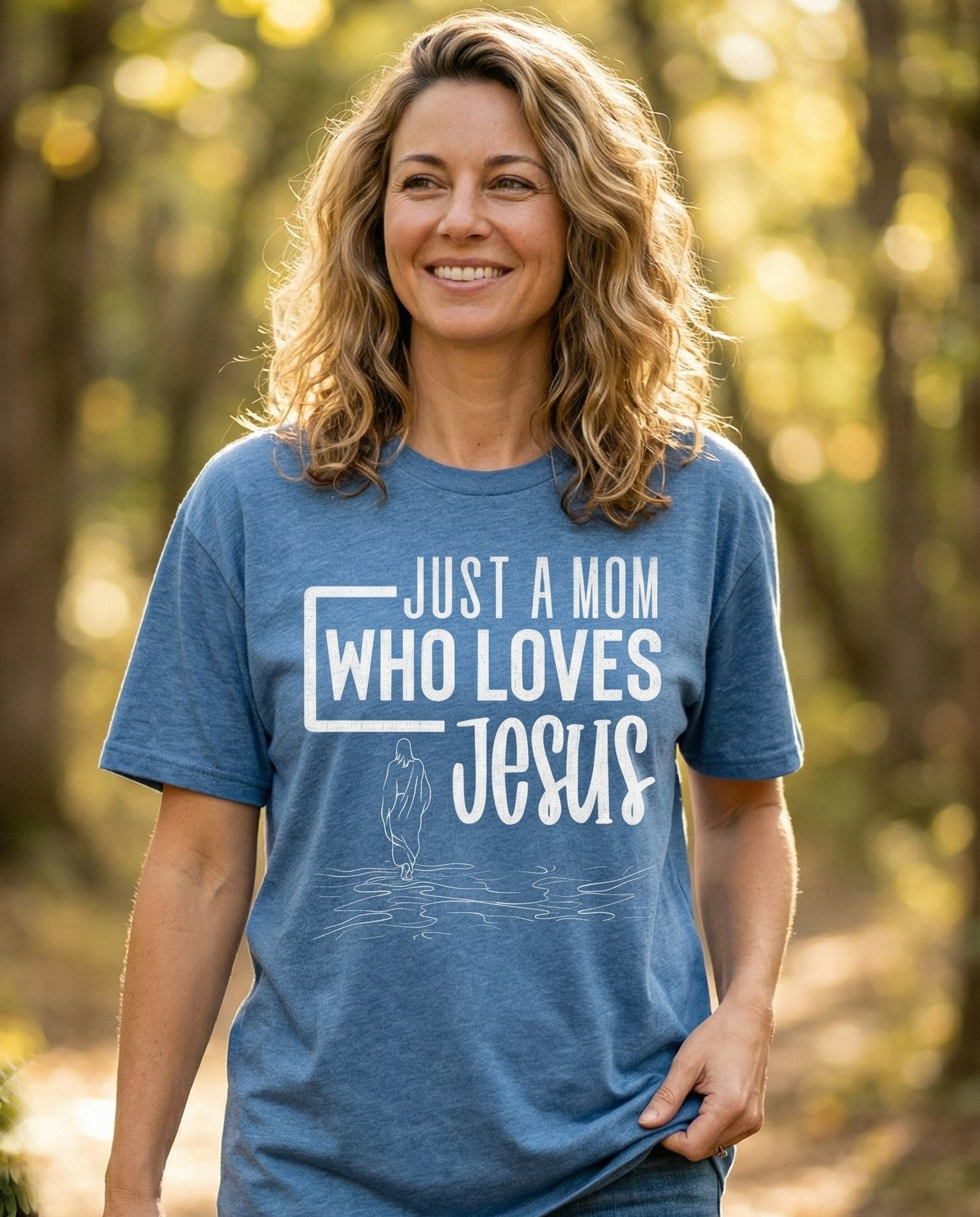 Mum Loves Jesus – Blue Jean women's Christian tee, lifestyle photo in nature trail – Bold block text reading 'Just a Mom Who Loves Jesus' with a minimal li – She Wears Faith