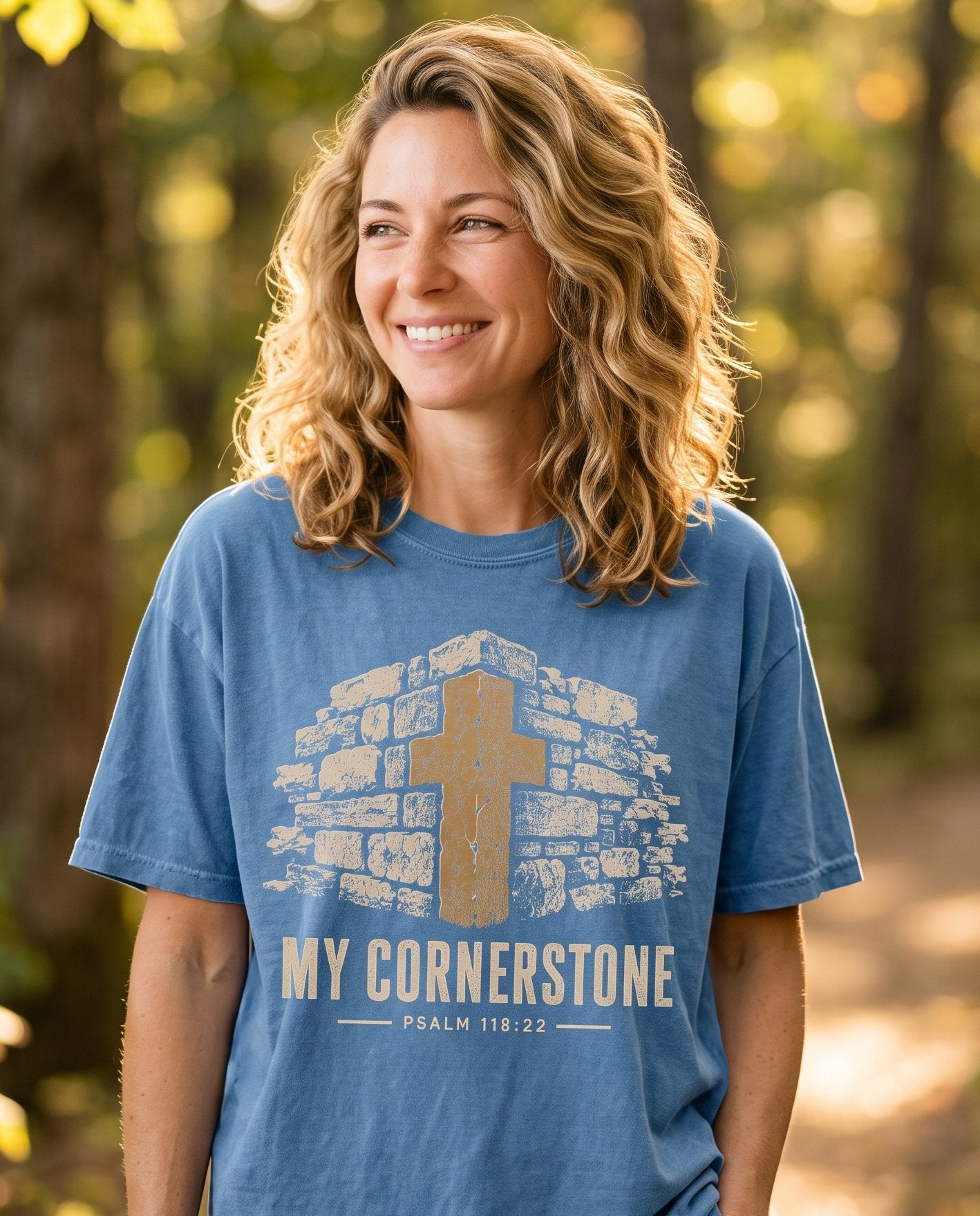 My Cornerstone Ps 118:22 – Blue Jean women's Christian tee, lifestyle photo in nature trail – A tan stone archway with a mustard-brown weathered cross rising from t – Psalm 118:22 – She Wears Faith