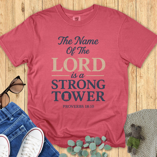 Comfort Colors 1717 crimson “The Name of the Lord is a Strong Tower – Proverbs 18:10” t-shirt flatlay styled with casual denim outfit. A bold and uplifting women’s scripture tee, great as a Christian mom gift idea.