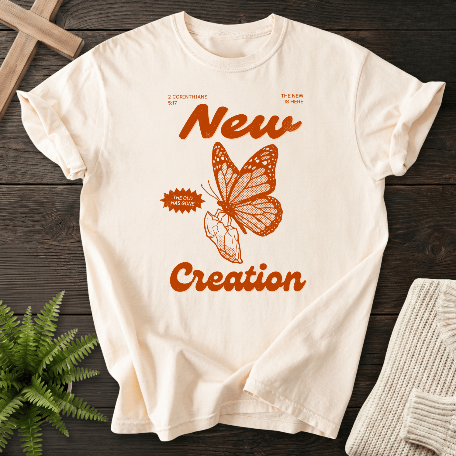 Ivory women's faith t-shirt with retro monarch butterfly and 'New Creation' orange script, inspired by 2 Corinthians 5:17.