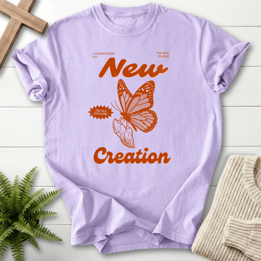 Orchid women's faith t-shirt with monarch butterfly and bold orange 'New Creation' lettering, inspired by 2 Corinthians 5:17.