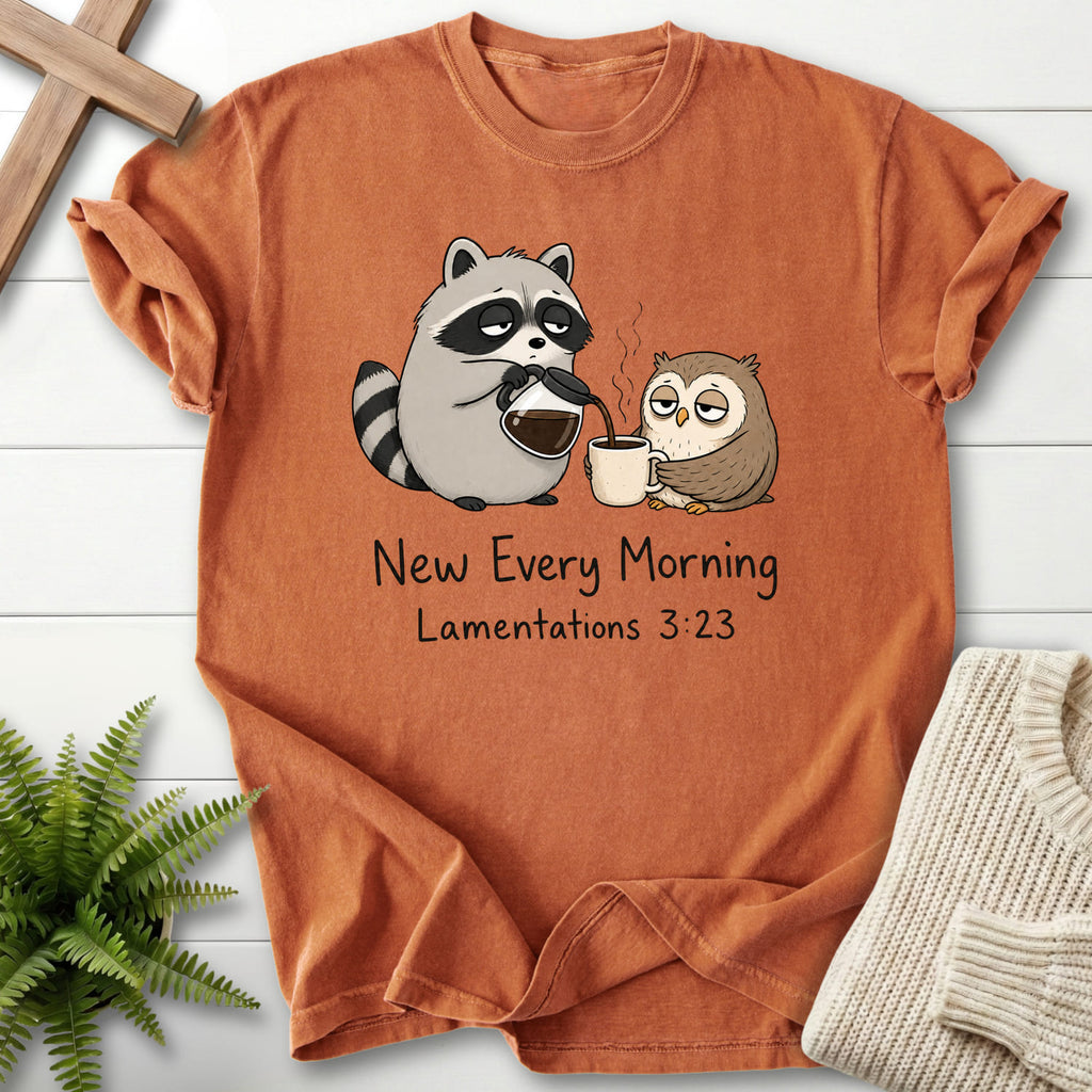 Flat lay of a Yam Christian graphic tee featuring "New Every Morning Raccoon Owl T-Shirt" Lamentations 3:23.