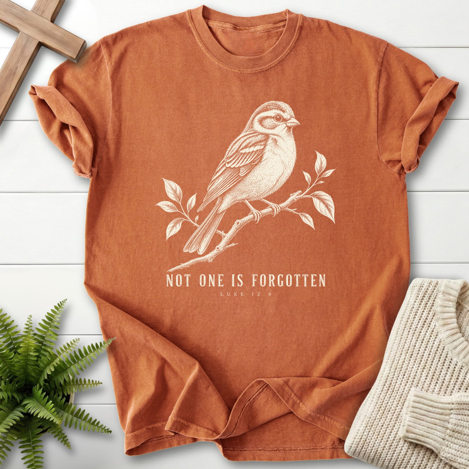 Flat lay of a Yam women's Christian tee featuring "Not One Is Forgotten Luke 12:6 T-Shirt" design.