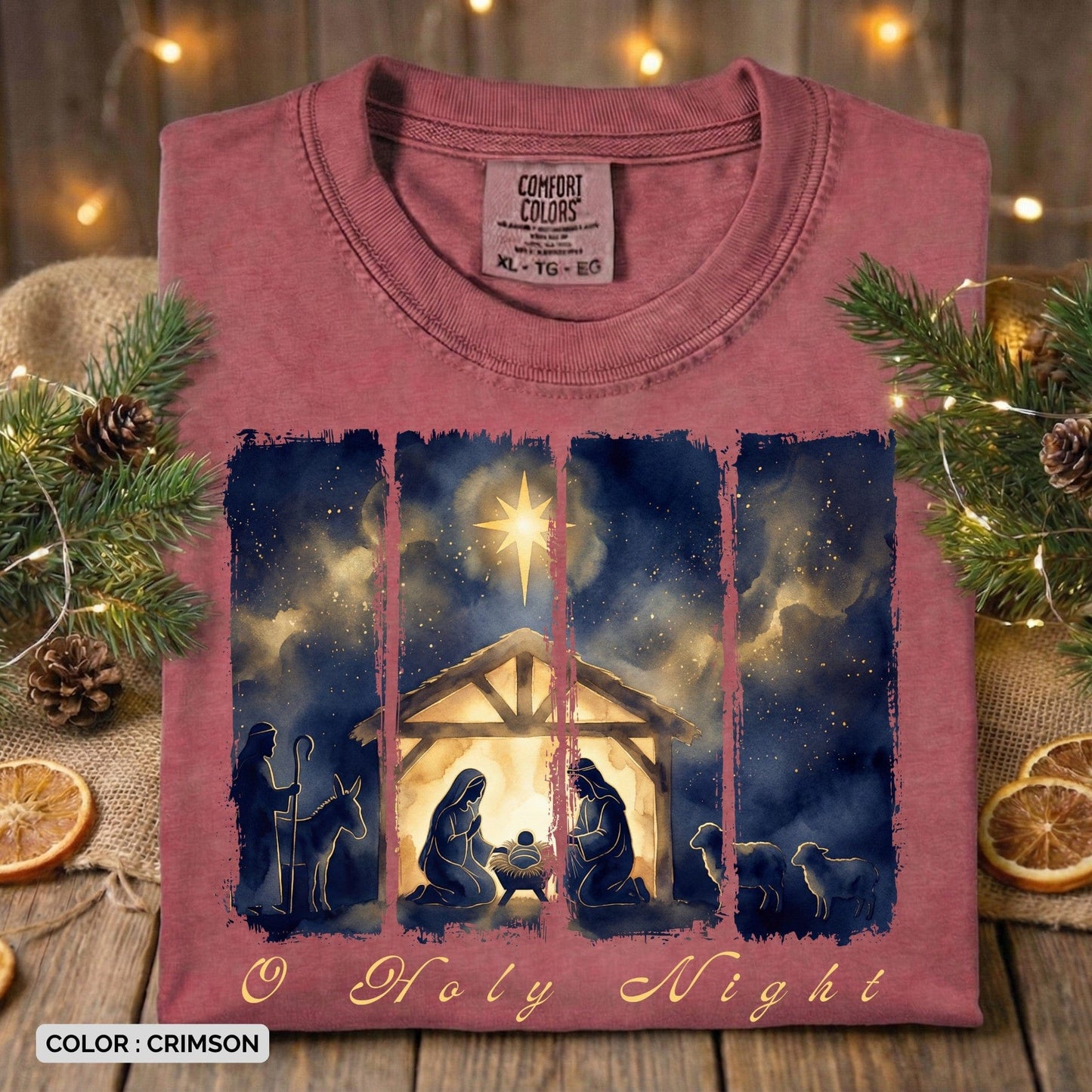 Folded Comfort Colors 1717 crimson Christian women tee featuring a watercolor “O Holy Night” nativity scene with Mary, Joseph, baby Jesus, shepherds, and the Star of Bethlehem. A warm and festive US faith wear Christmas T-shirt styled with pine greenery and lights.