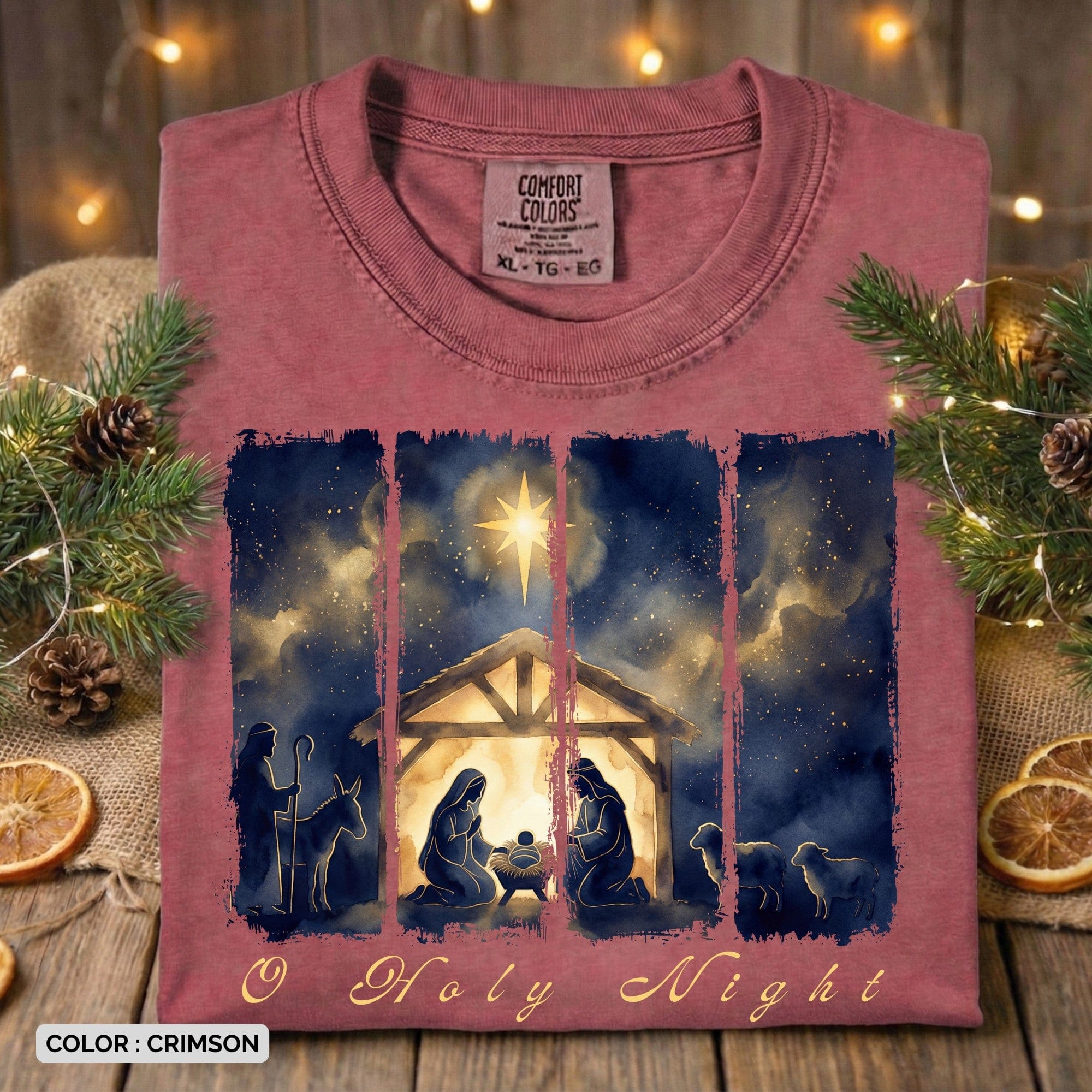 Folded Comfort Colors 1717 crimson Christian women tee featuring a watercolor “O Holy Night” nativity scene with Mary, Joseph, baby Jesus, shepherds, and the Star of Bethlehem. A warm and festive US faith wear Christmas T-shirt styled with pine greenery and lights.