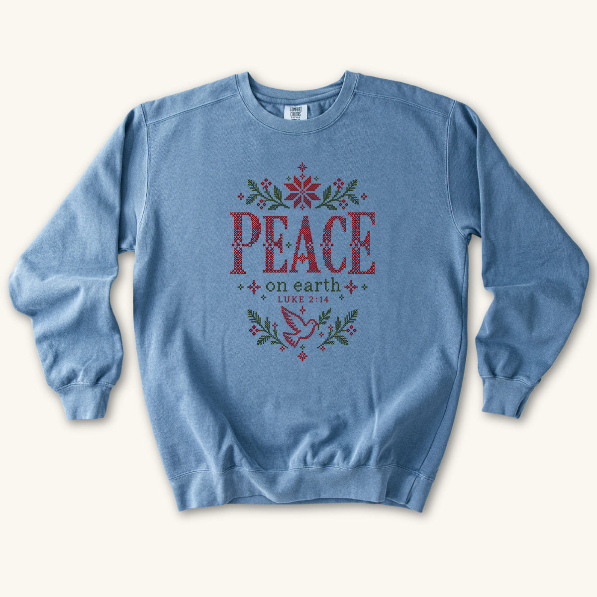 Blue Jean Christian Christmas sweatshirt with cross-stitch style Peace on Earth lettering, a dove, stars, branches and Luke 2:14.