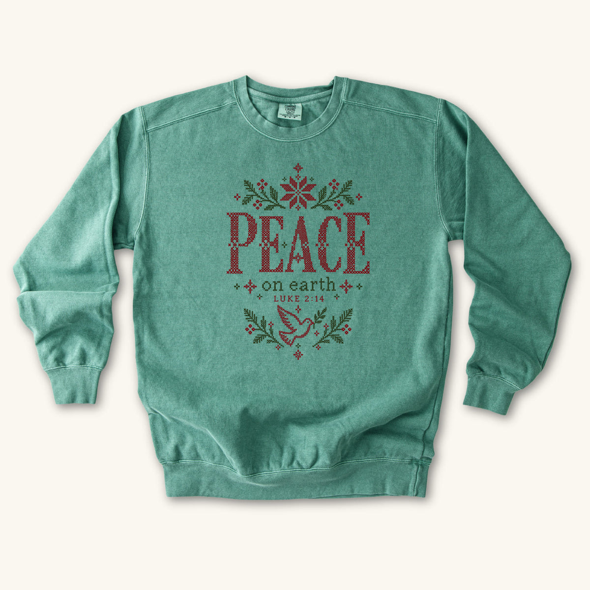 Light Green Christian Christmas sweatshirt with cross-stitch style Peace on Earth lettering, a dove, stars, branches and Luke 2:14.