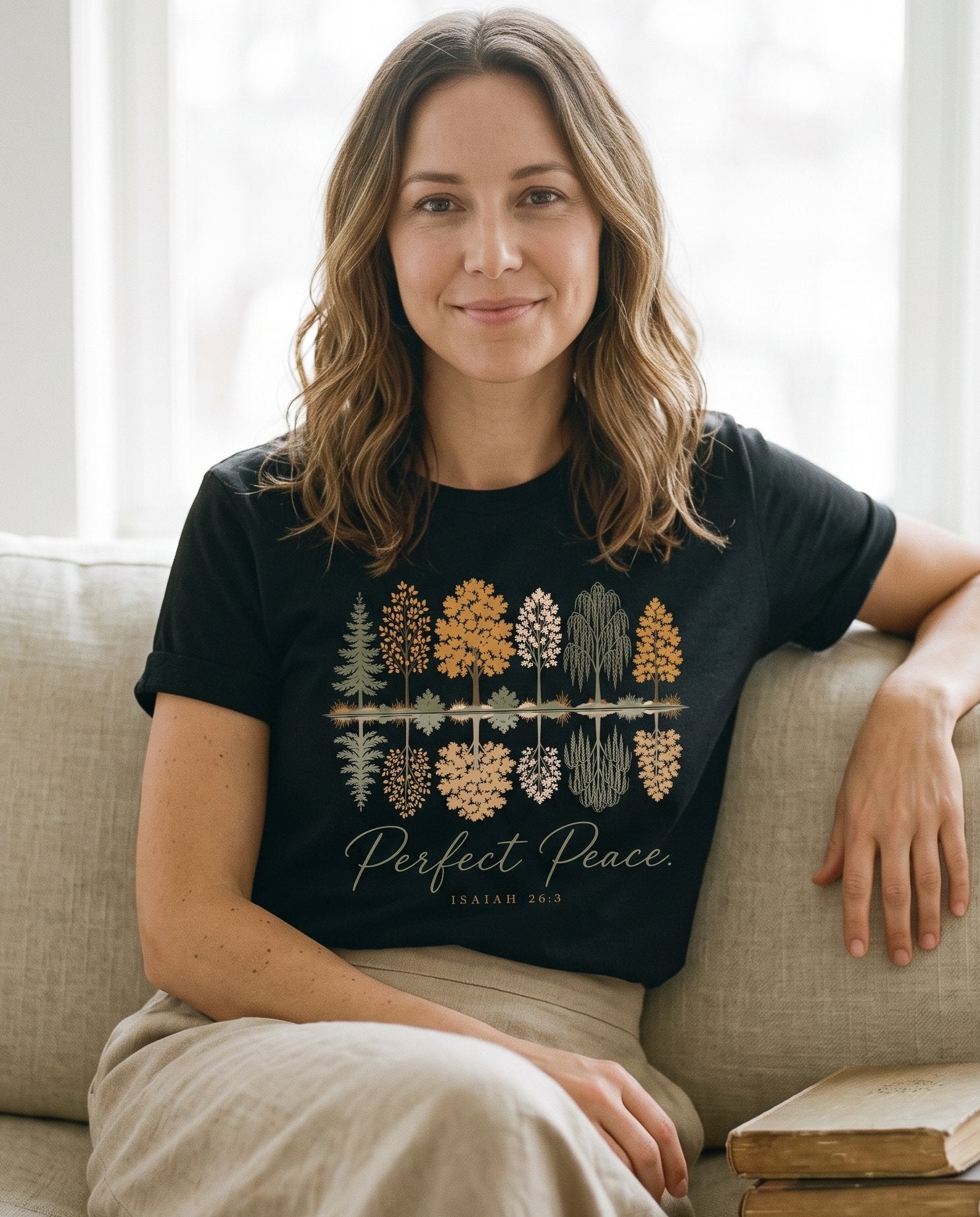 Perfect Peace Isaiah 26 3 – Black women's Christian tee, lifestyle photo in cozy living room – Illustrated trees reflected in still water beneath flowing script "Per – Isaiah 26:3 – She Wears Faith
