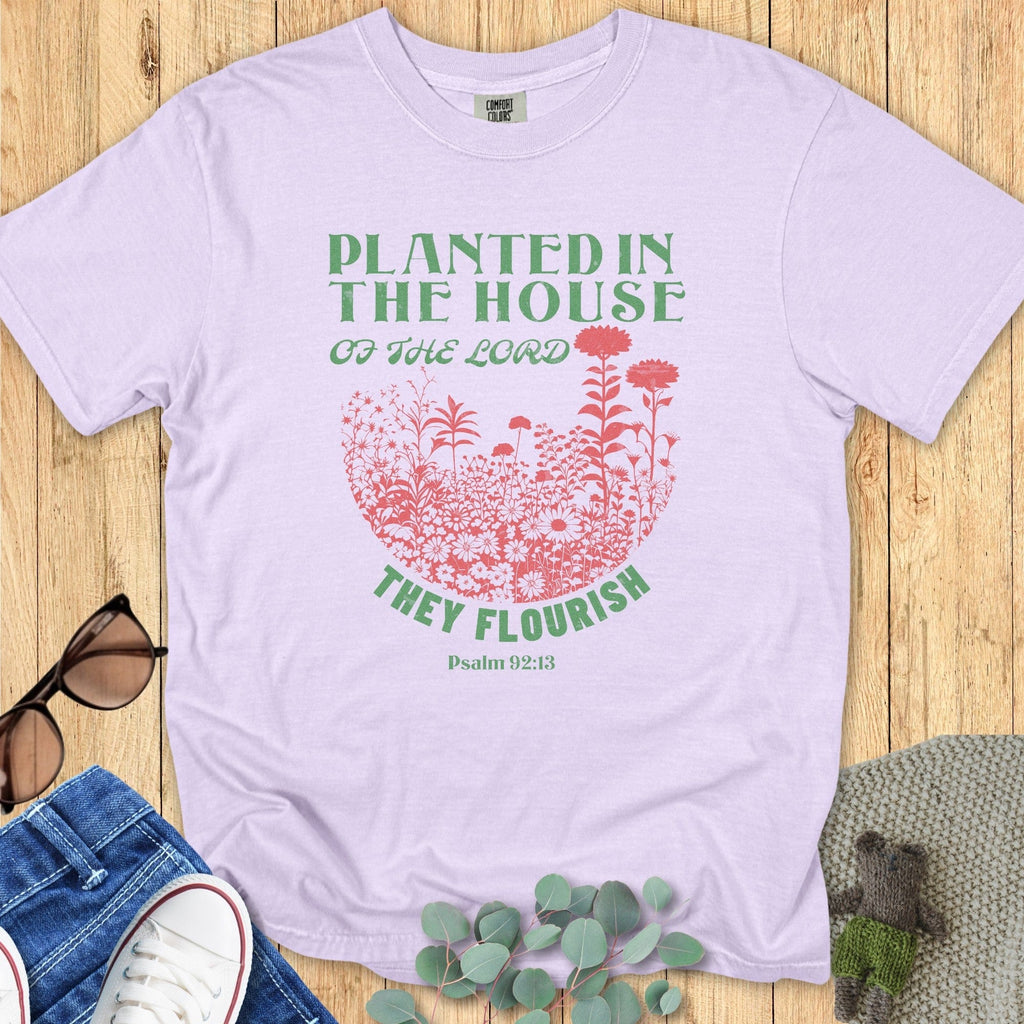 Flat lay of an Orchid Comfort Colors 1717 tshirt featuring a wildflower garden design. A pastel Christian women tee with "Planted in the House of the Lord" Psalm 92:13 scripture, ideal for US faith wear.
