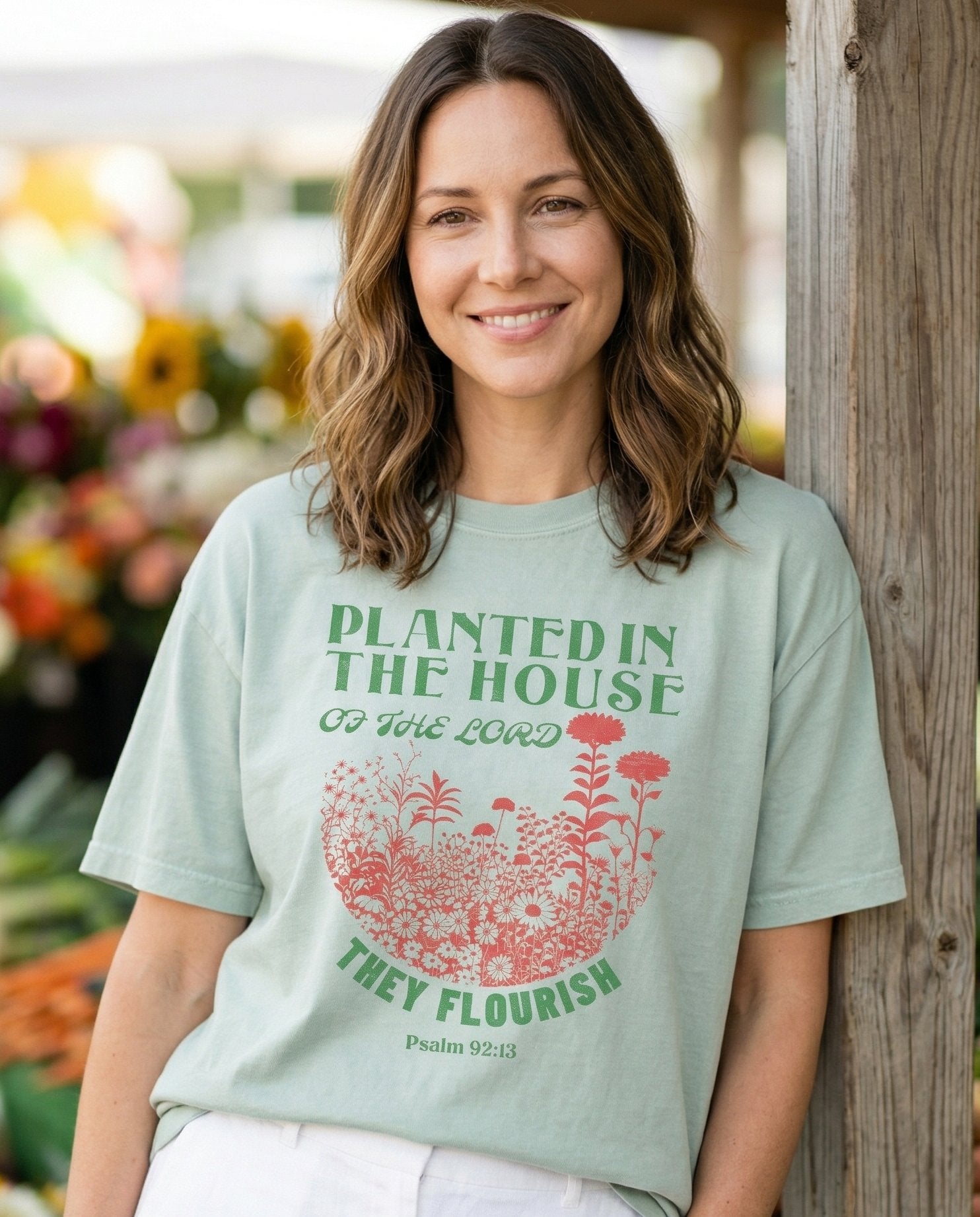 Planted in the House Christian – Bay women's Christian tee, lifestyle photo in farmers market – Retro botanical design with a semicircle of colorful wildflowers and t – Psalm 92:13 – She Wears Faith