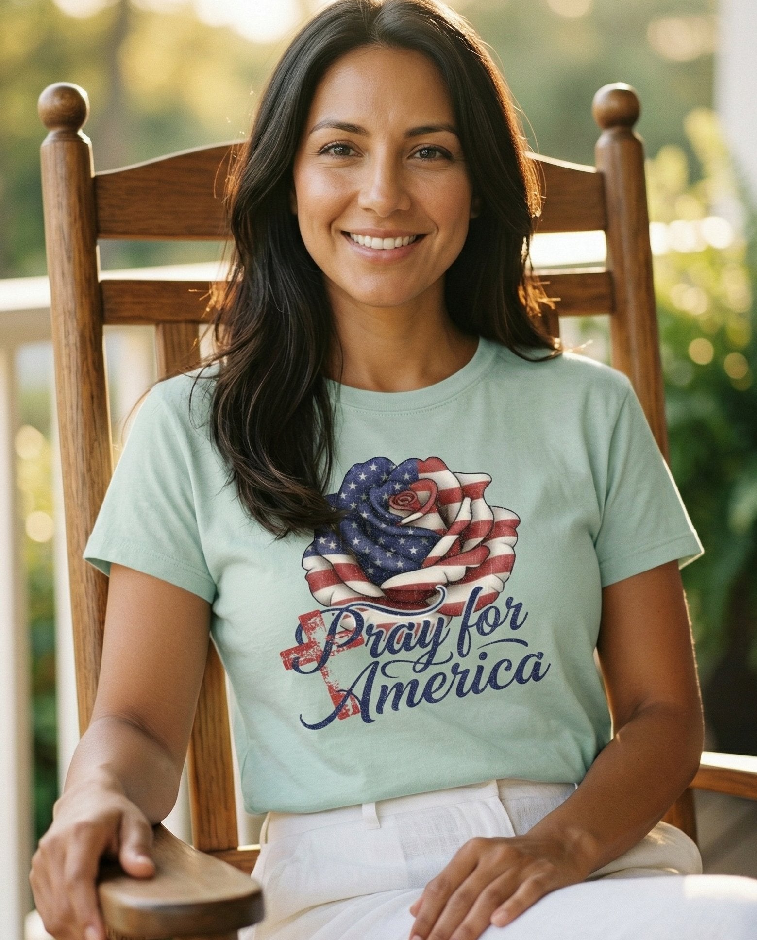 Pray for America – Bay women's Christian tee, lifestyle photo in sunny porch – Patriotic rose graphic with American flag stars and stripes forming th – She Wears Faith