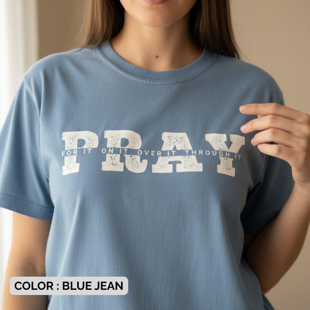 Woman wearing a Comfort Colors 1717 blue jean “PRAY for it, on it, over it, through it” t-shirt with bold distressed lettering. A casual women’s scripture tee -  faith-based apparel for women and modern Christian shirt, perfect Christian mom gift idea for daily encouragement.