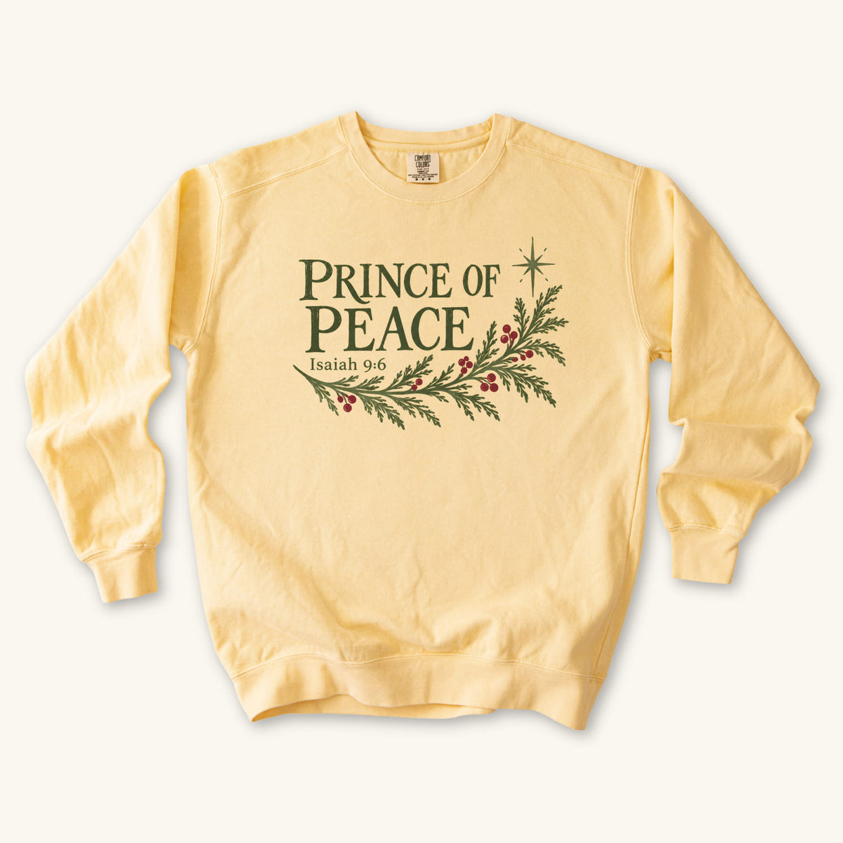 Butter Christian Christmas sweatshirt with Prince of Peace lettering, an evergreen branch with red berries, a star and Isaiah 9:6.