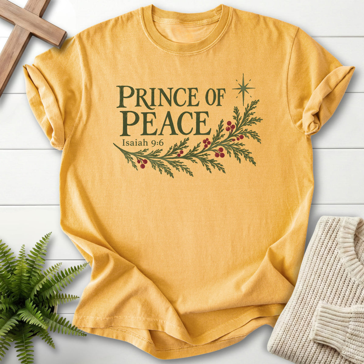 Flatlay of a Mustard Scripture shirt with vine and grape artwork with "Prince of Peace T-Shirt" Isaiah 9:6.