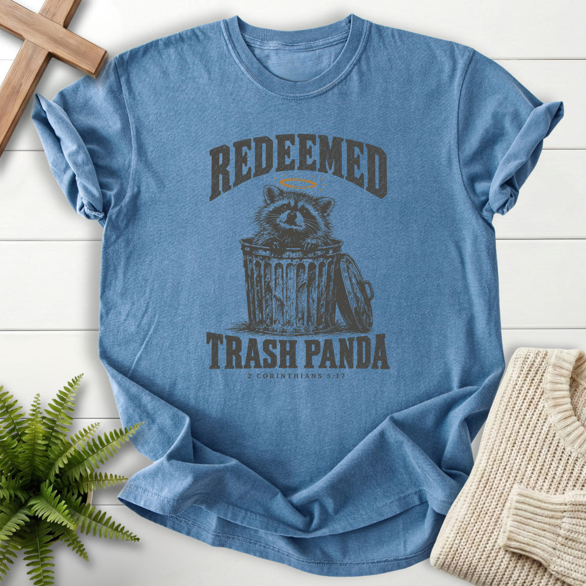Blue Jean Redeemed Trash Panda T-shirt flat lay mockup, 2 Corinthians 5:17 Christian apparel for women