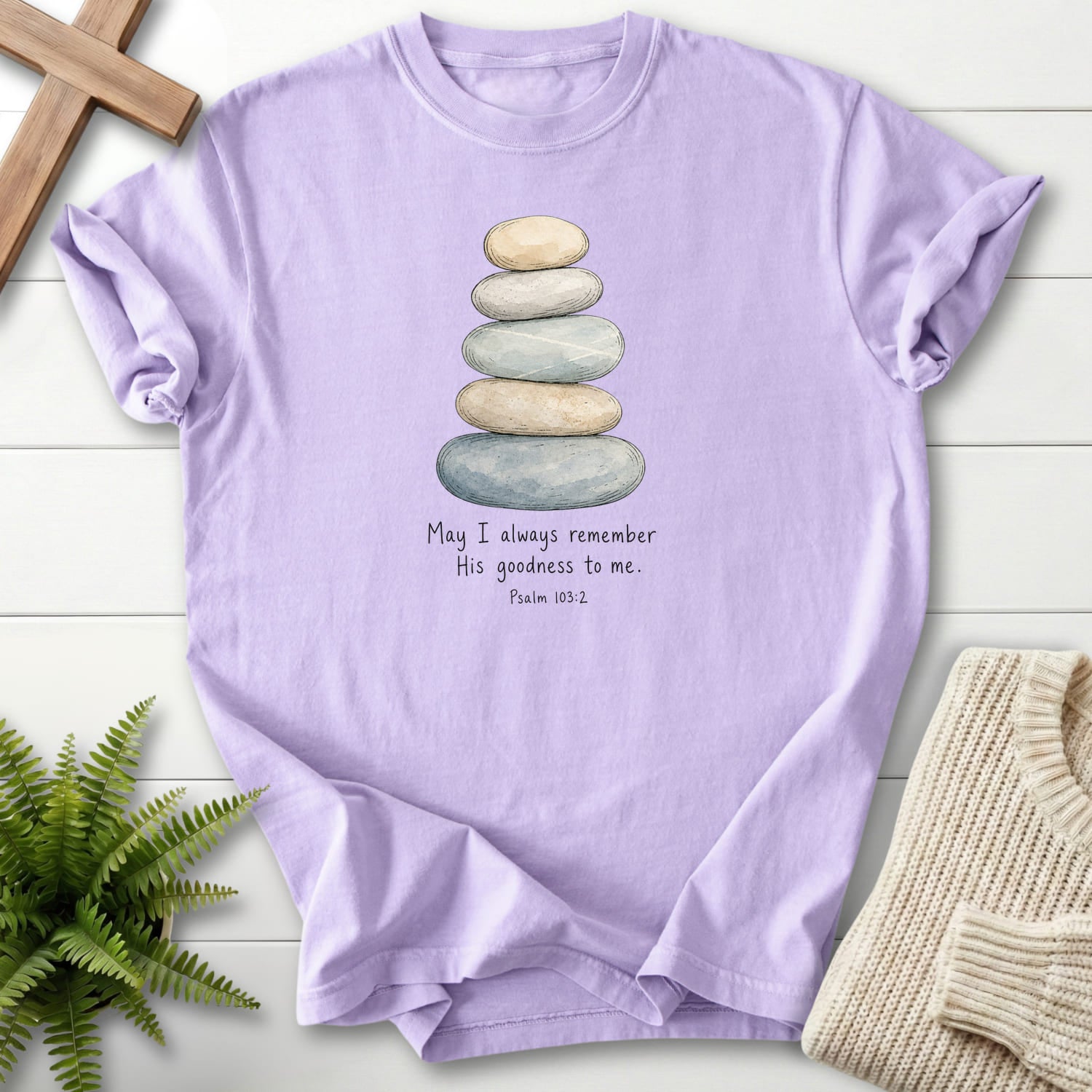 Flatlay of an Orchid faith-based tee with "Remember His Goodness Dark T-Shirt" Psalm 103:2.