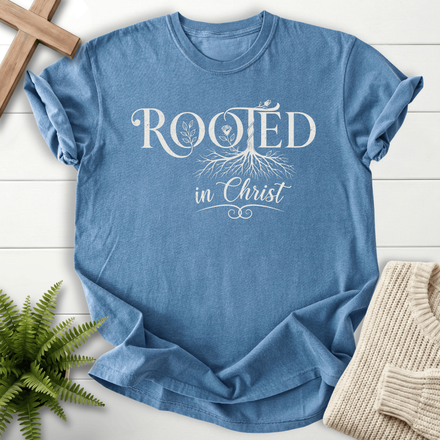Blue Jean women's Bible verse tee with Rooted in Christ botanical motif and a small bird accent.